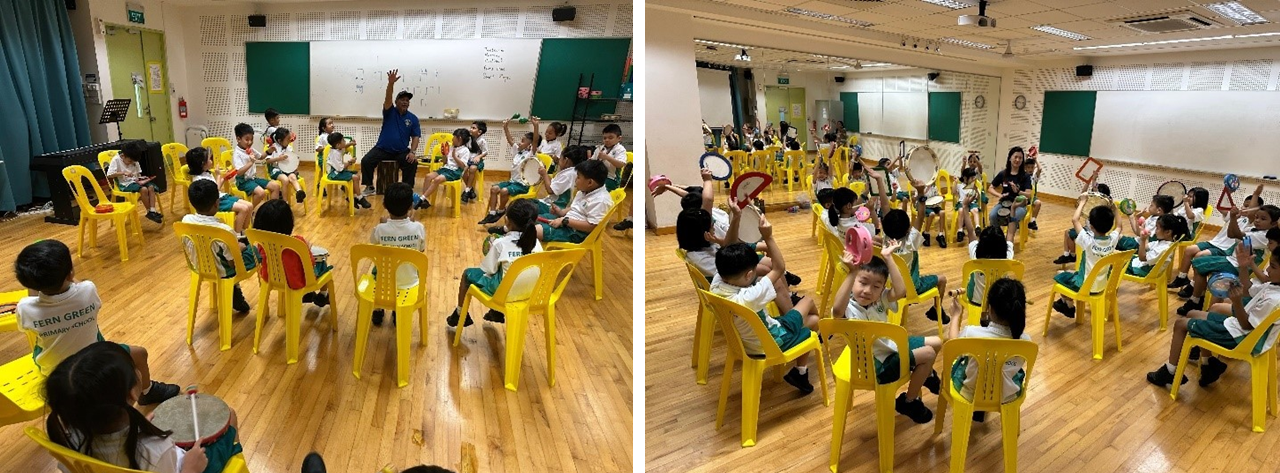 Young students in white uniforms sit on yellow chairs in a circle, holding instruments during a music class with a teacher.