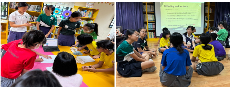 Students in uniforms gather around a yellow table in a library and sit in a circle on a floor near a presentation screen.