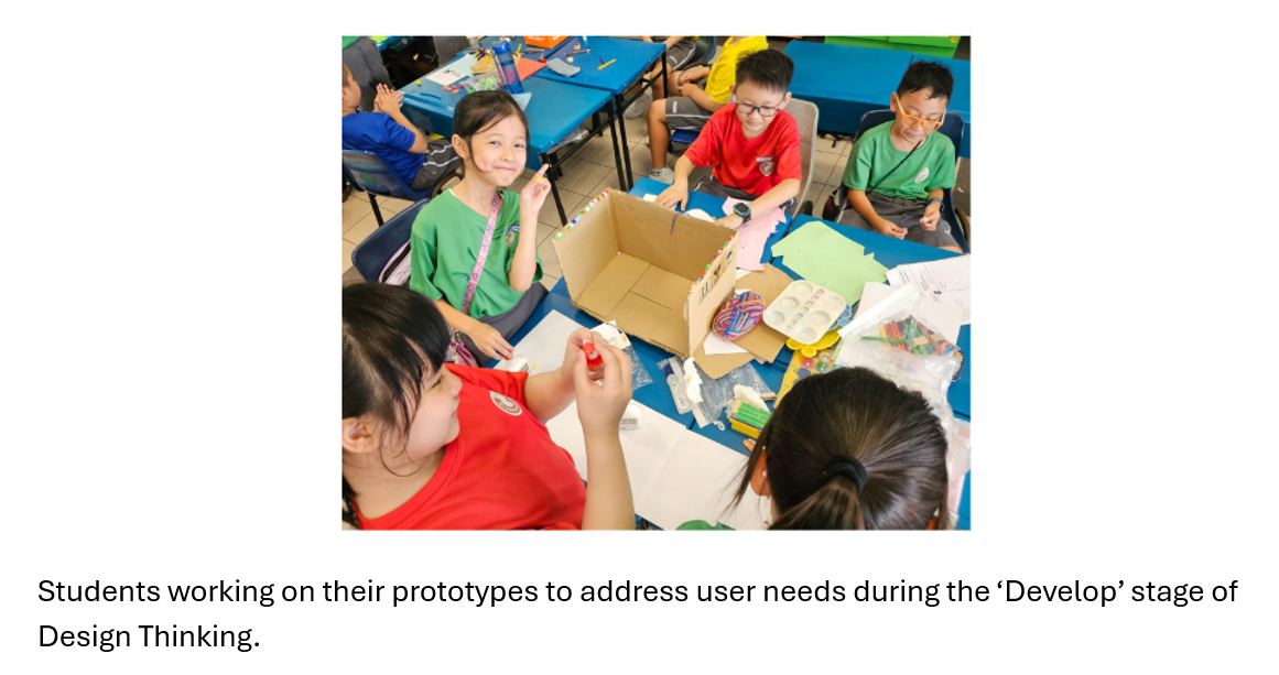 Children in school uniforms sit around a blue table building prototypes with cardboard and craft supplies.