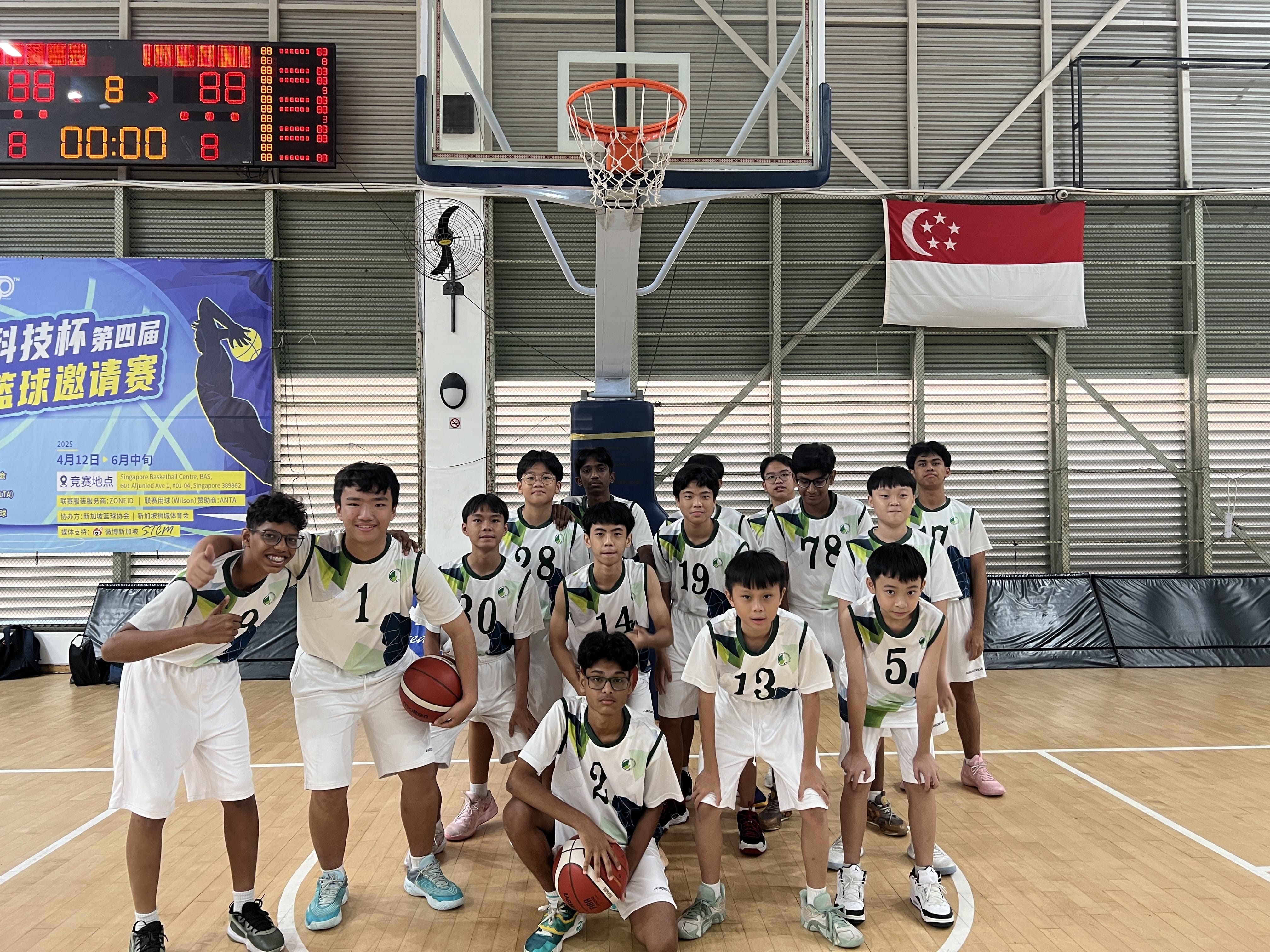 The Jurongville Secondary School boys' basketball team posing together under the hoop at an indoor basketball court.