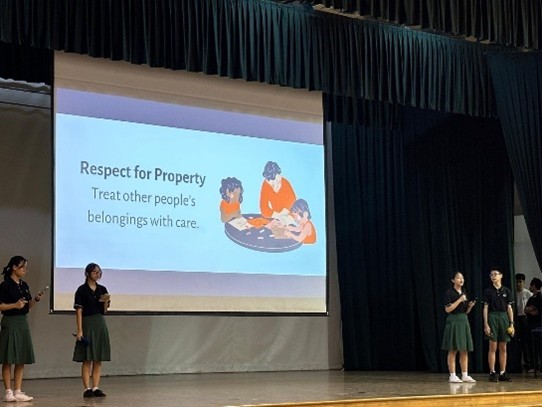 Members of the Student Council leading a cohort-wide assembly presentation on stage, highlighting peer education and character values advocacy.