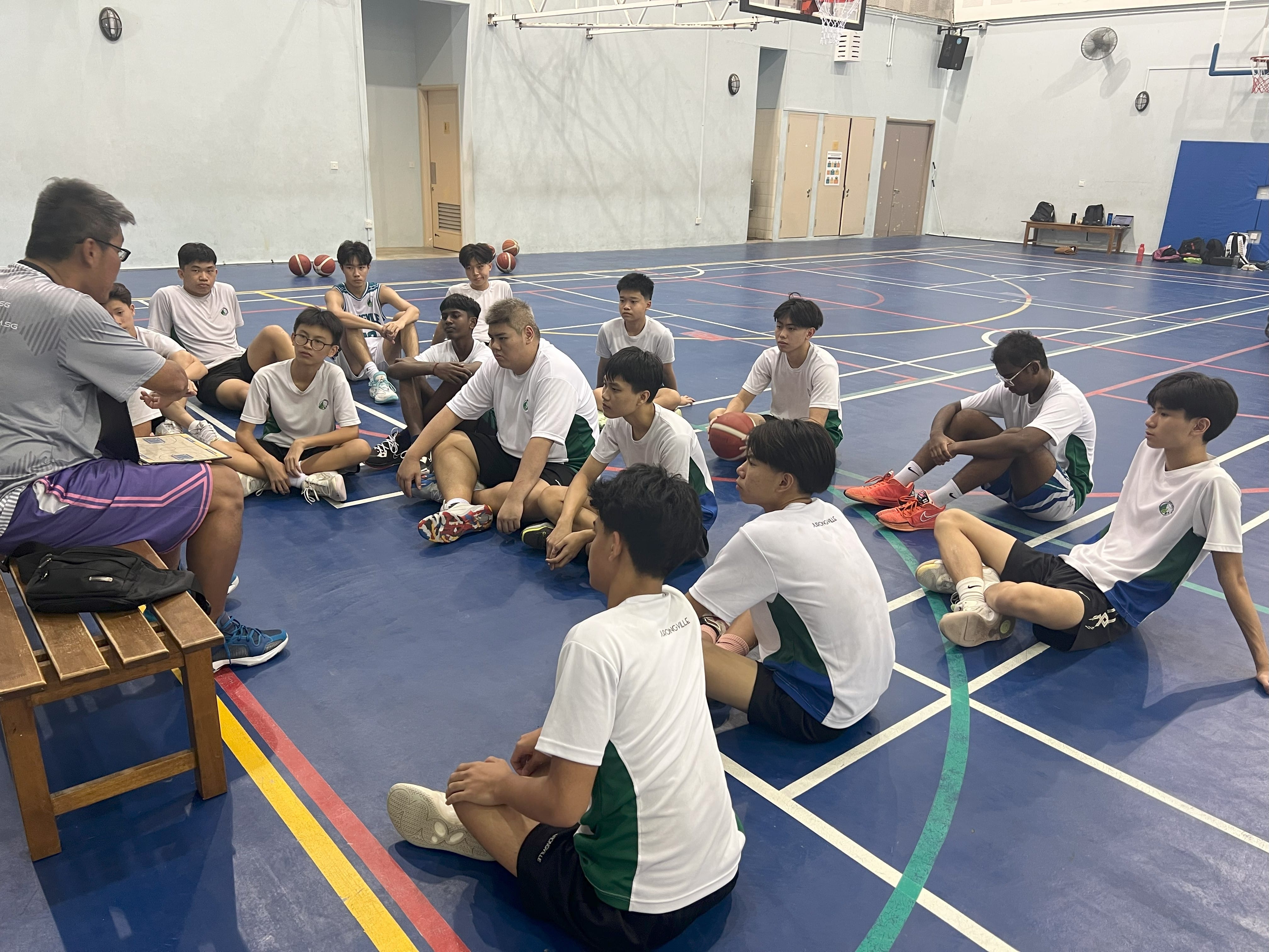 A briefing or tactical review session for the Jurongville Secondary School boys' basketball team.