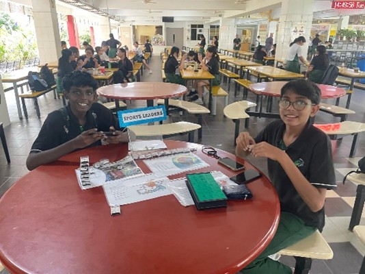 An information or recruitment booth managed by Sports Leaders in the school canteen during a student outreach or post-school event.
