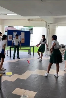 An interactive recreational game of capteh hosted in a school courtyard, highlighting a traditional sports station organized and refereed by Sports Leaders.