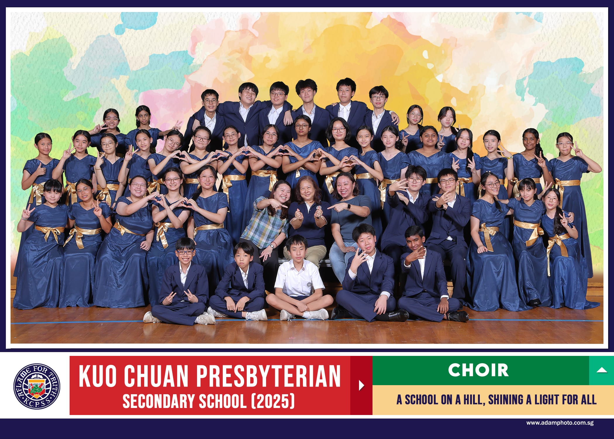 Group photo of Kuo Chuan Presbyterian Secondary School 2025 Choir in navy and gold uniforms posing together.