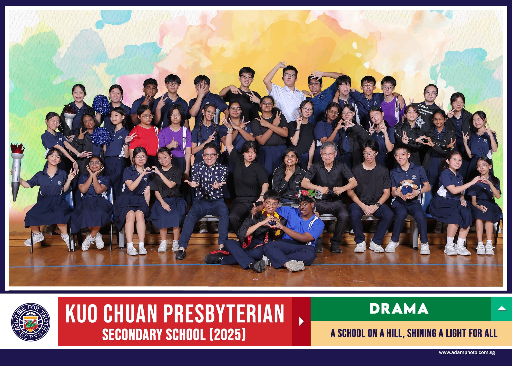 Group photo of Kuo Chuan Presbyterian Secondary School 2025 Drama club members posing with hand gestures indoors.
