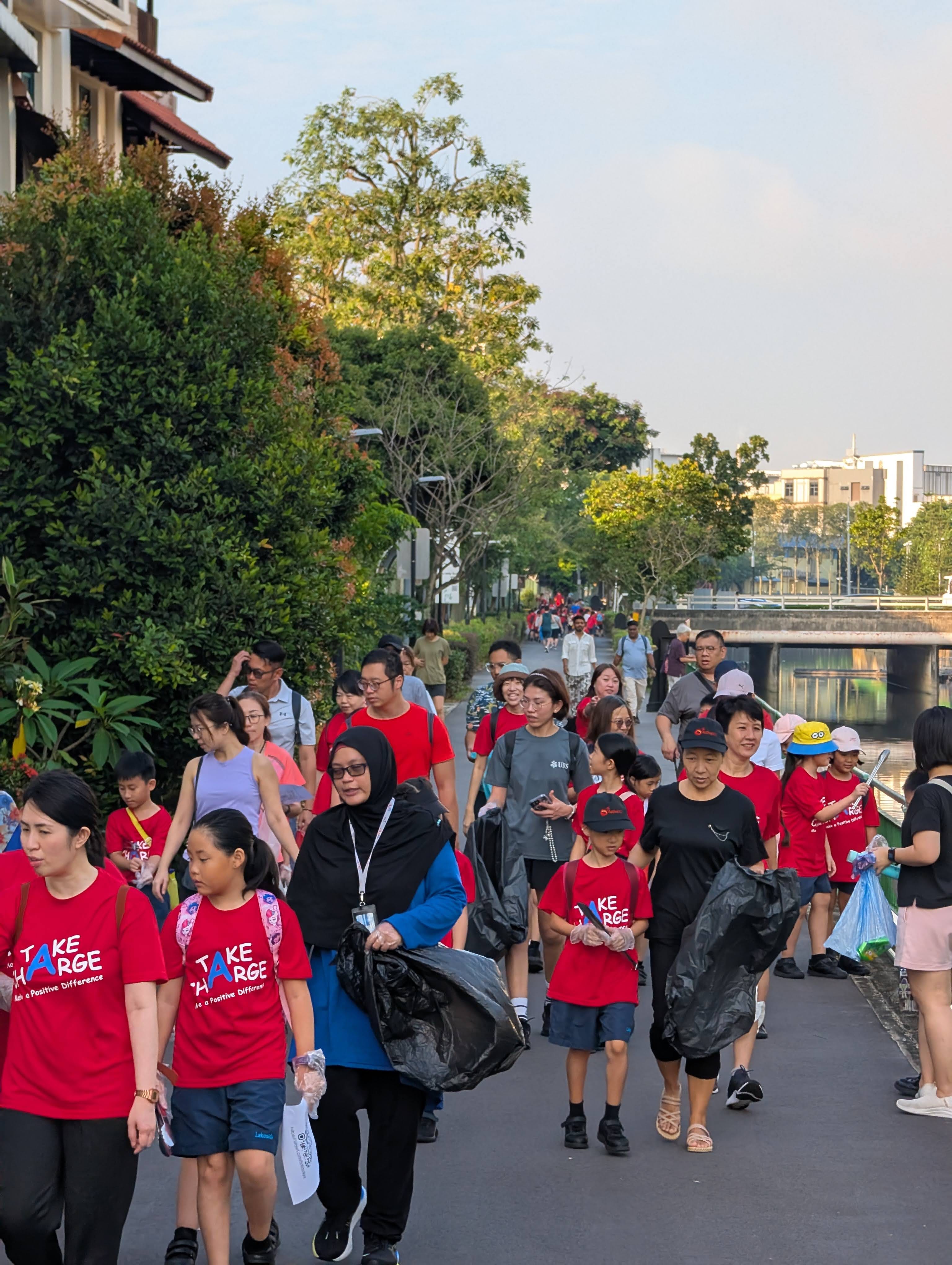 Students and their families walking together down a path looking for litter to pick up from the ground