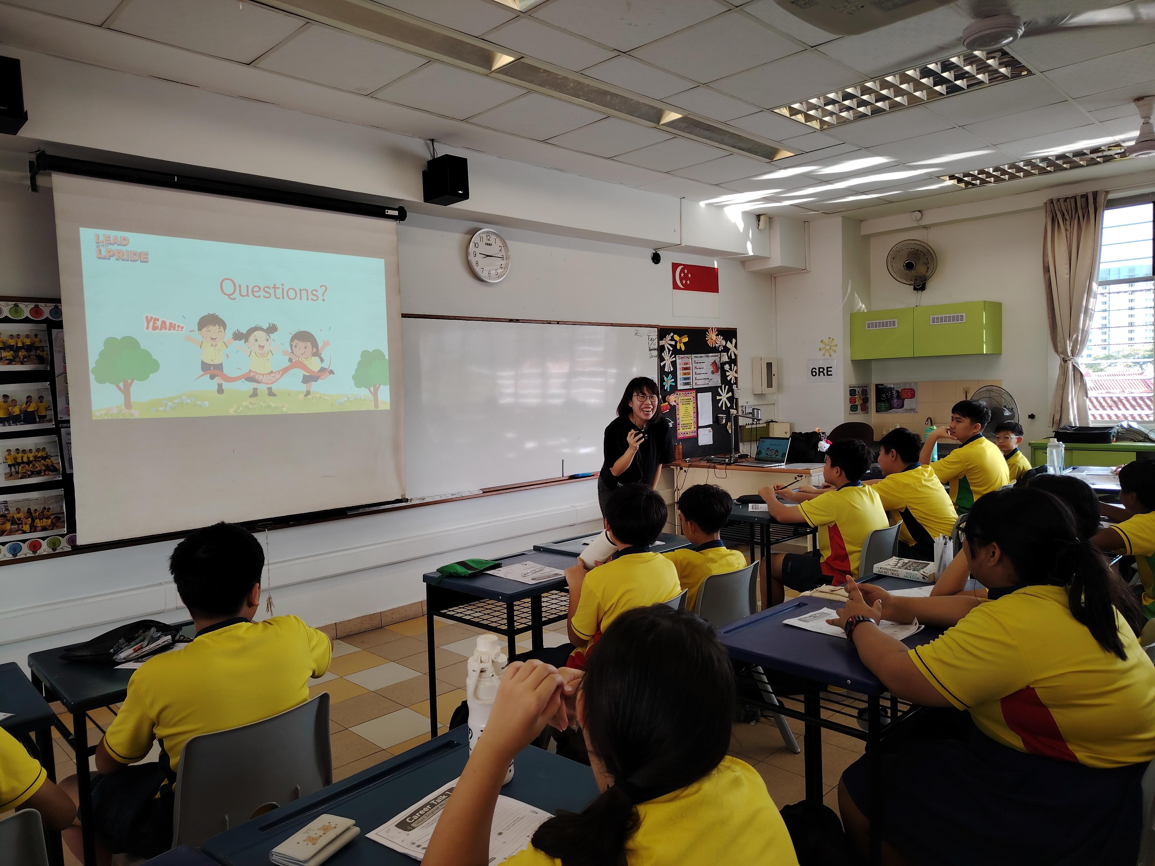 A Research Scientist speaks to a class of Primary 6 students, sharing insights into her career and the role of scientific research while students listen attentively.