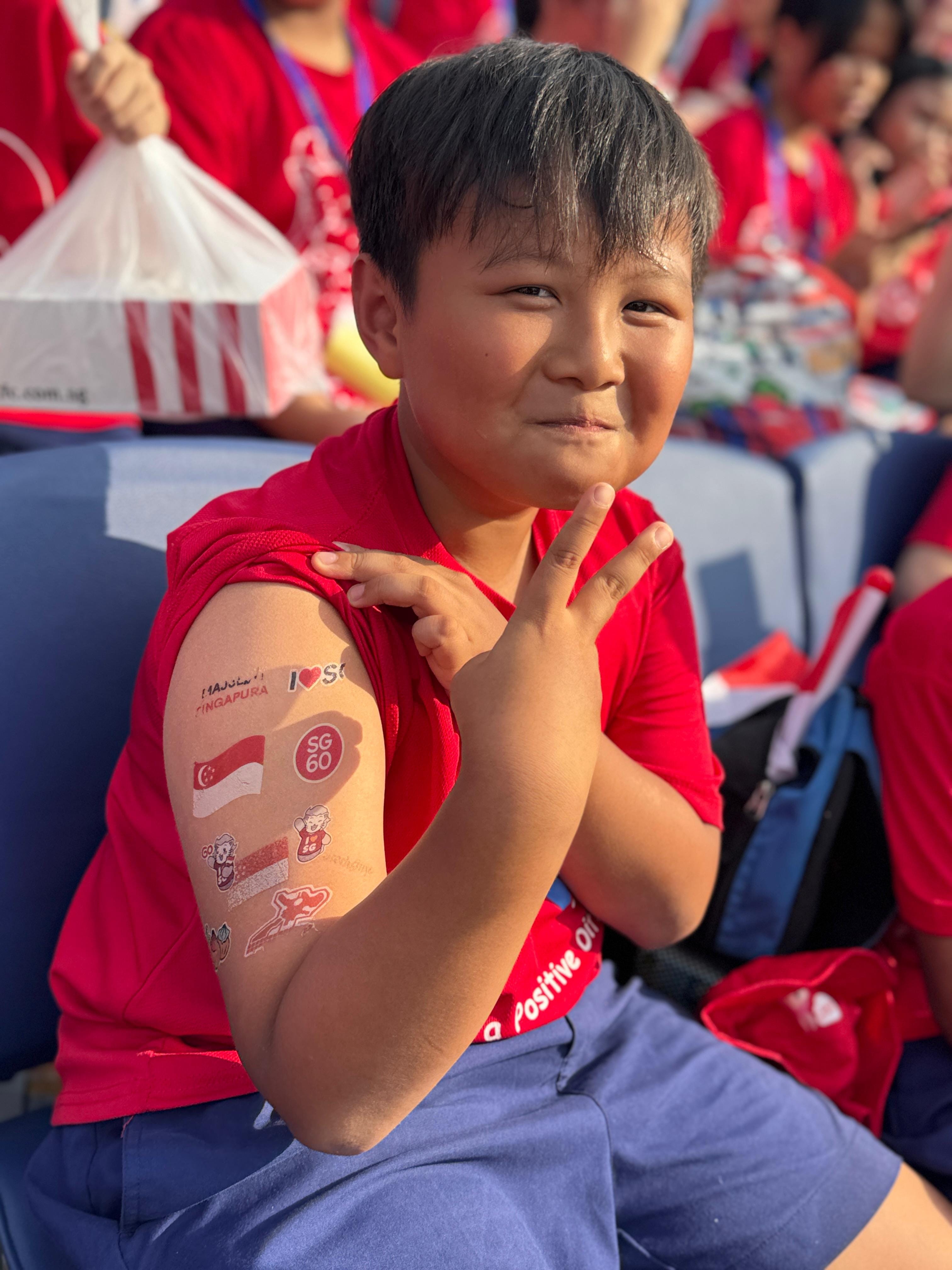 Student proudly showing off his temporary tattoos to express his excitement for Singapore's birthday celebration