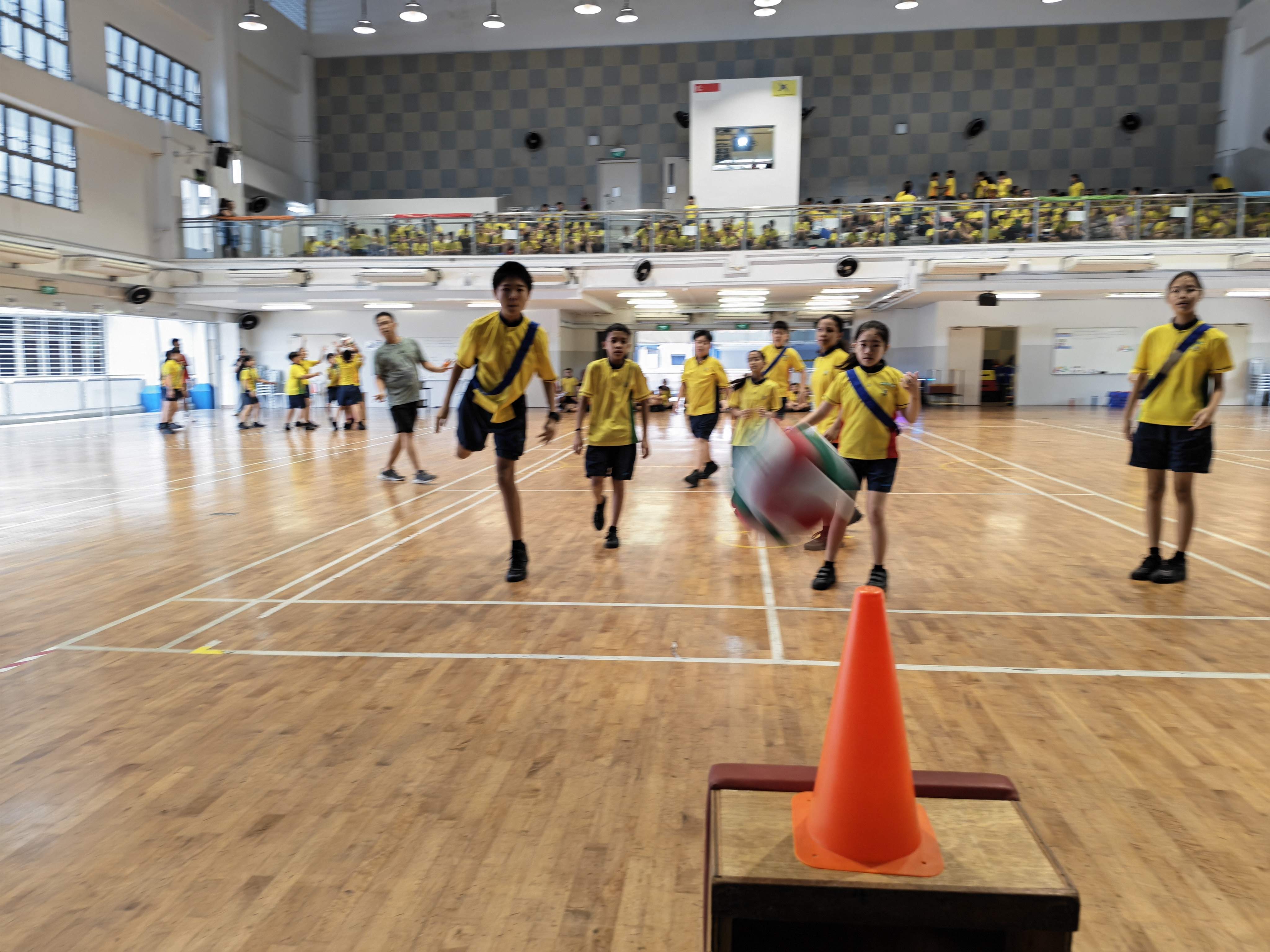 Students run and watch as a ball is about to hit a team's goal cone