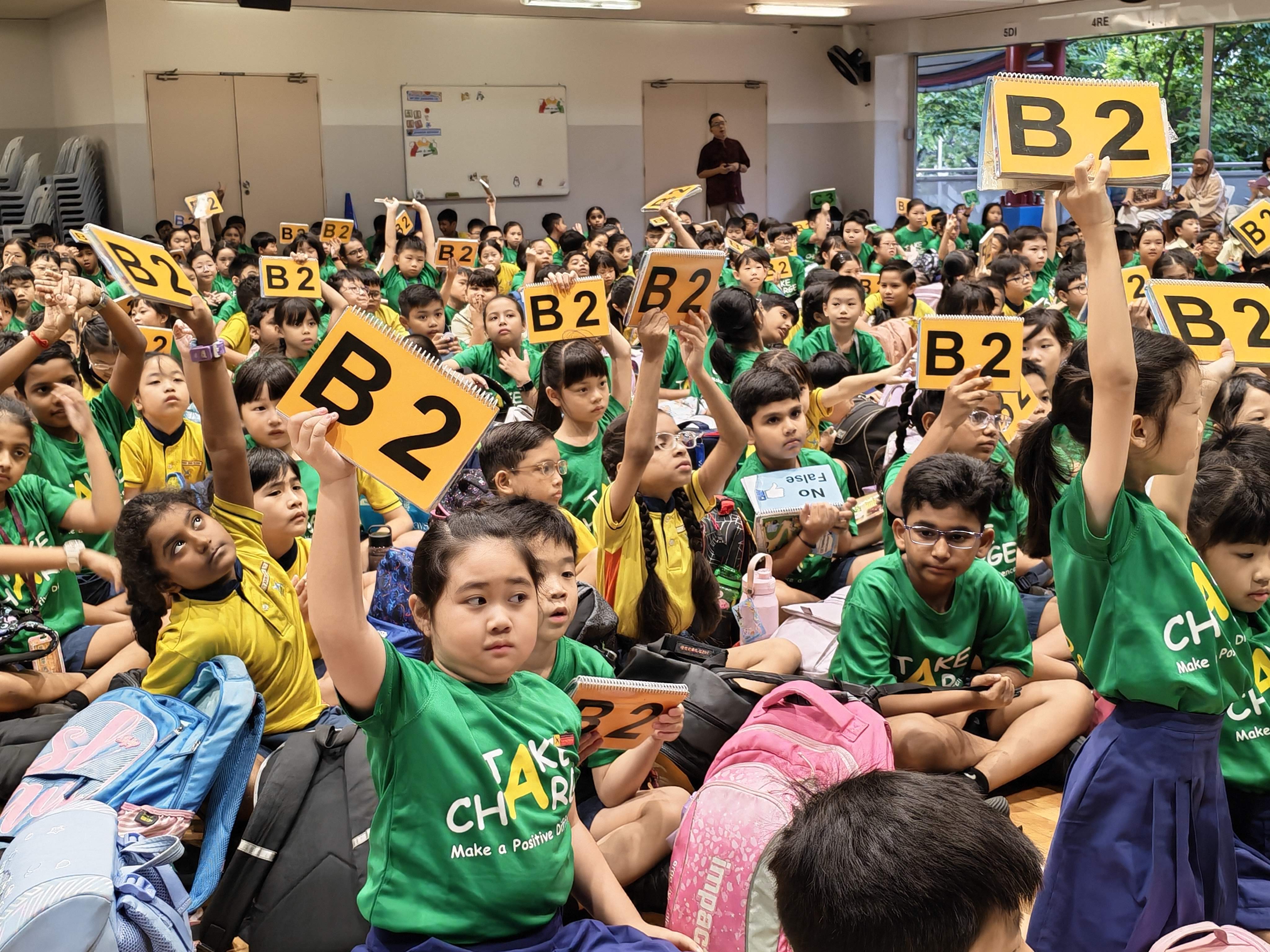 Students participate enthusiastically in an interactive Racial Harmony Day assembly by raising answer cards to answer questions.