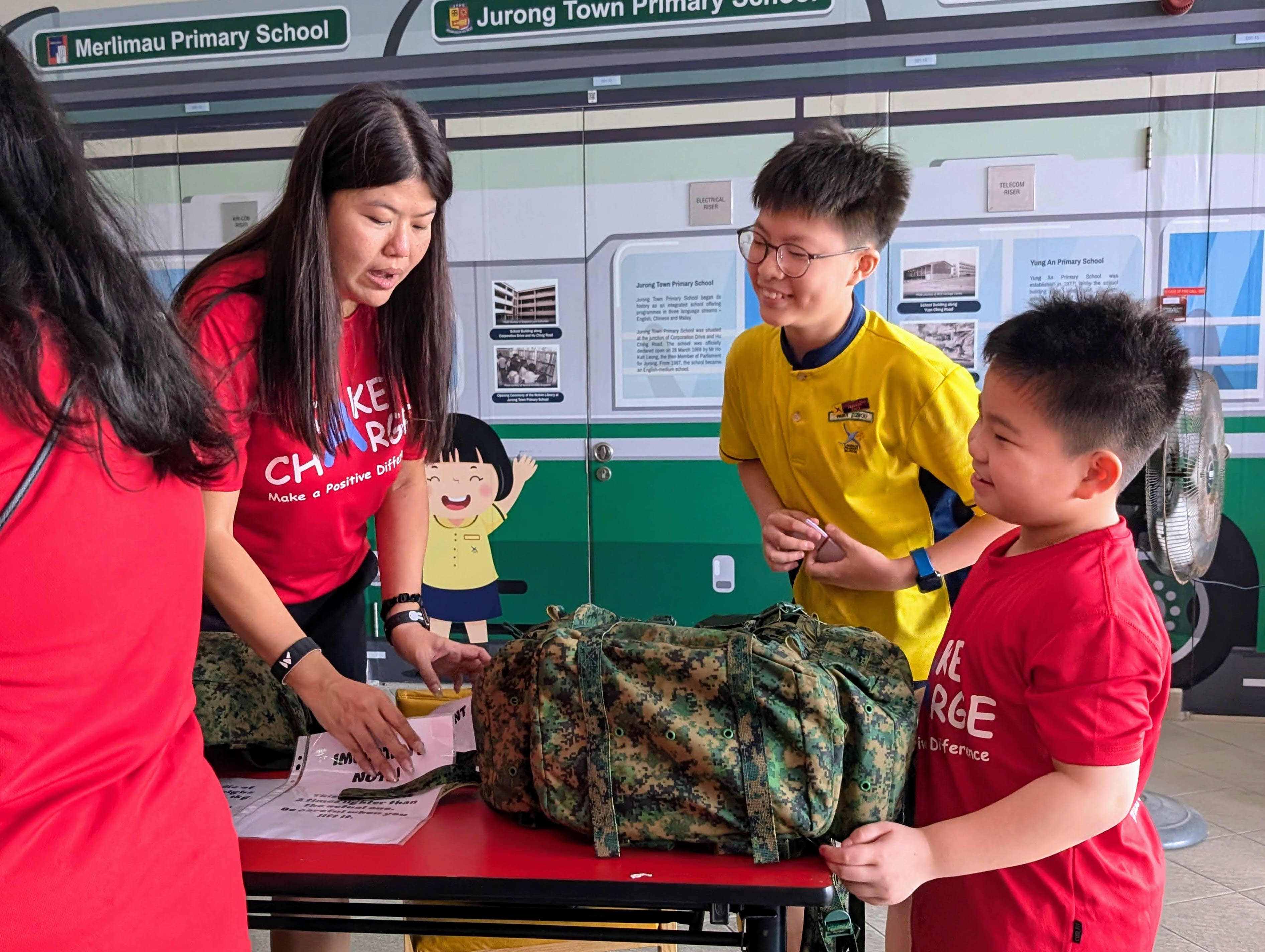 Two students gather around defence supplies as they estimate and compare the weight of the equipment at this fun activity booth