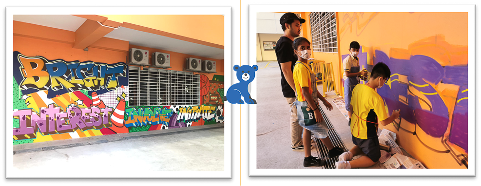 Colorful graffiti mural on a school wall beside students in yellow uniforms painting a purple and orange mural.