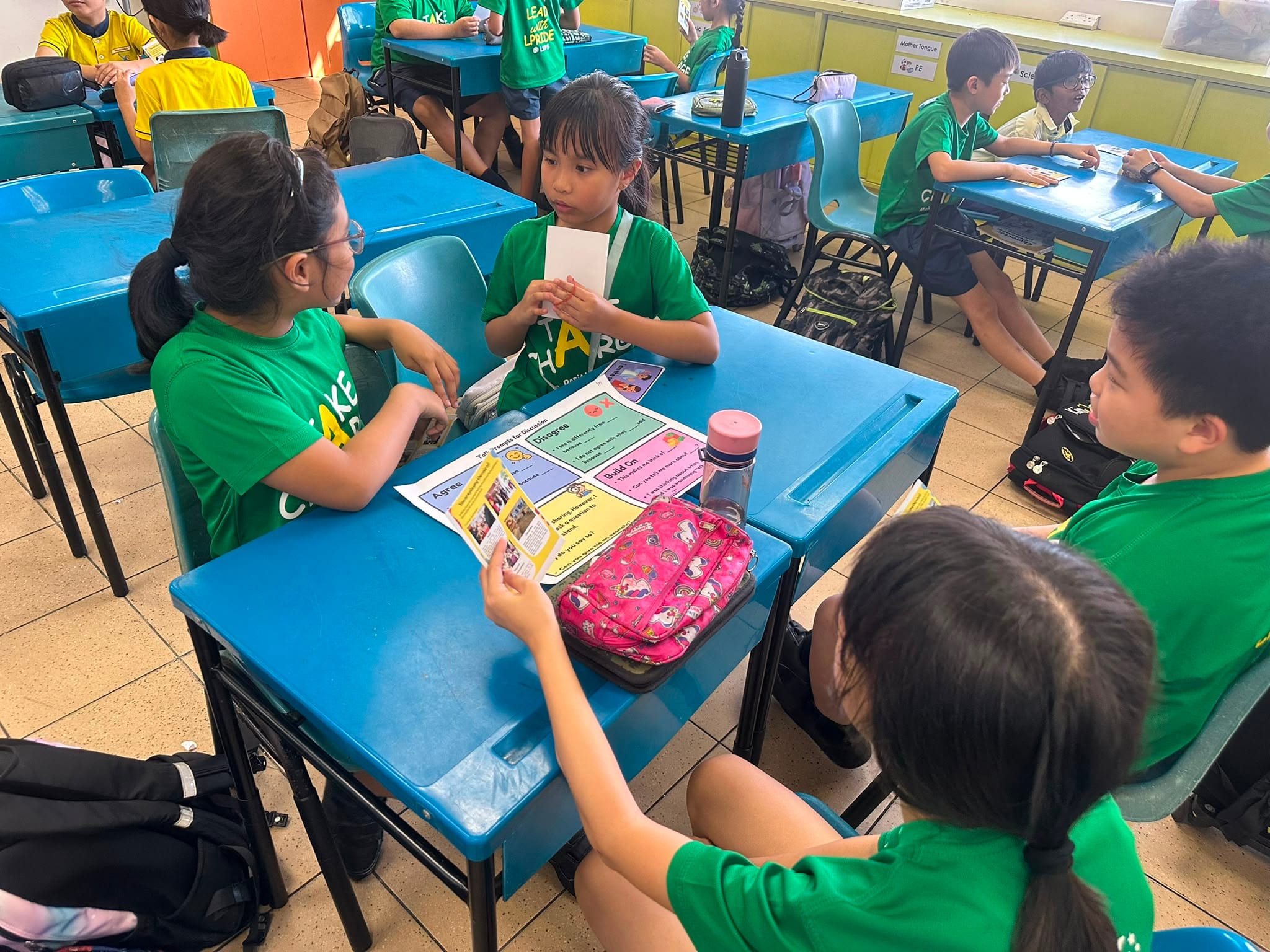Students participate in a collaborative classroom activity during Racial Harmony Day, discussing scenarios and learning to appreciate different viewpoints.