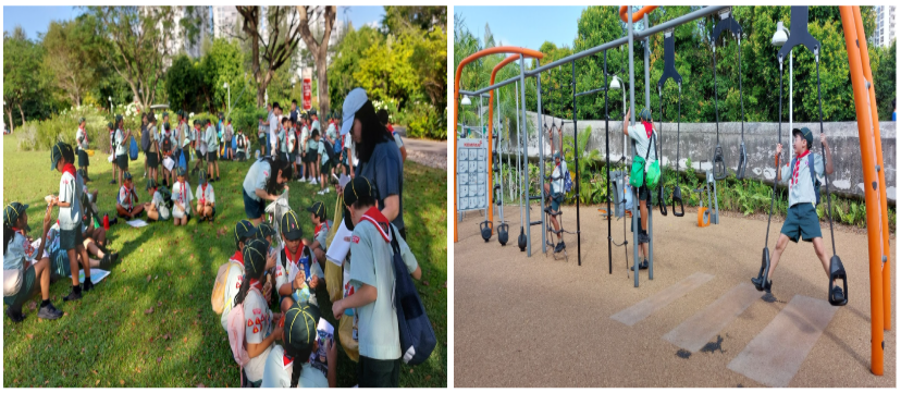 Scouts in uniform sit on grass in a park while another scout swings on playground equipment nearby.