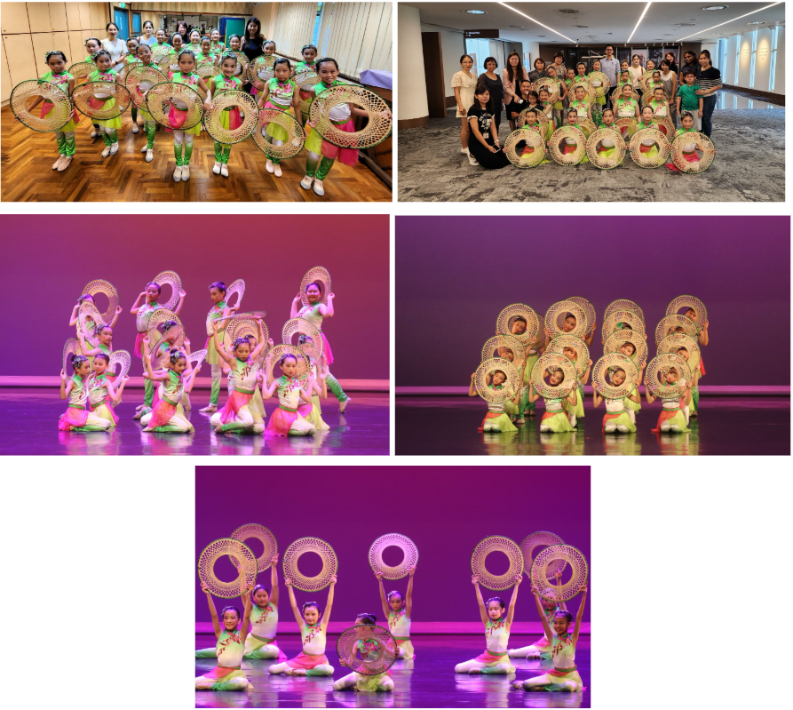 Young girls in colorful green and pink costumes perform a traditional Chinese fan dance on stage with round woven props.