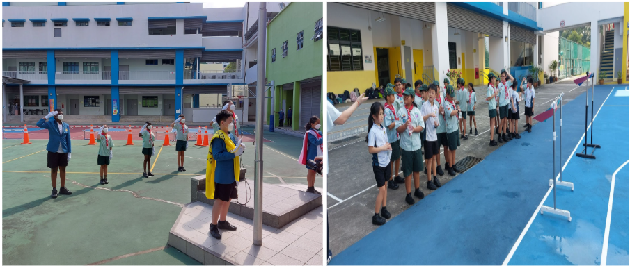 Students in uniforms stand at attention outdoors at a school, saluting near a flagpole on the left side.