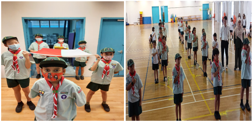 Children in scout uniforms with green hats and red scarves stand indoors, some holding a red and white flag.