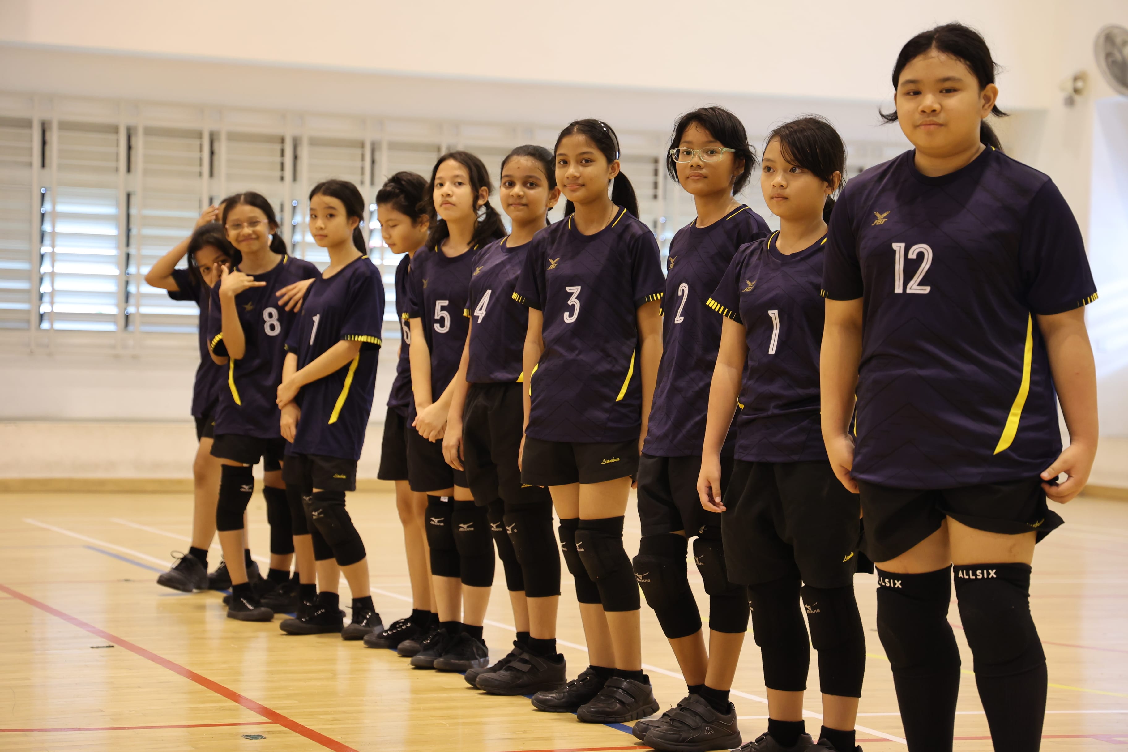 Volley ball girls stand in one row.