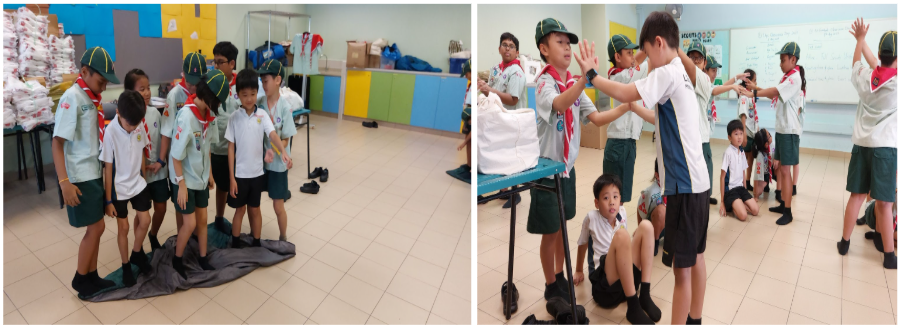Children in scout uniforms with green caps and red scarves participate in indoor activities in a classroom.
