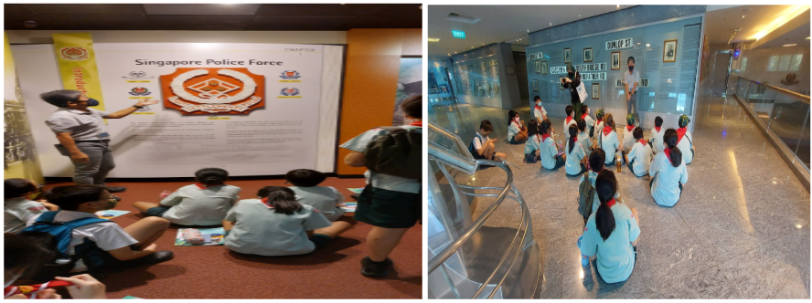 Students in school uniforms sit on the floor during a Singapore Police Force museum tour, listening to guides.