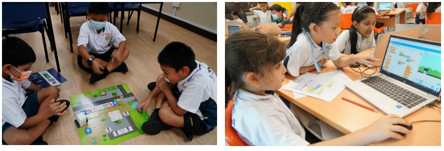 Young students in white uniforms work on a coding board game on the floor and use a laptop with Scratch programming software.