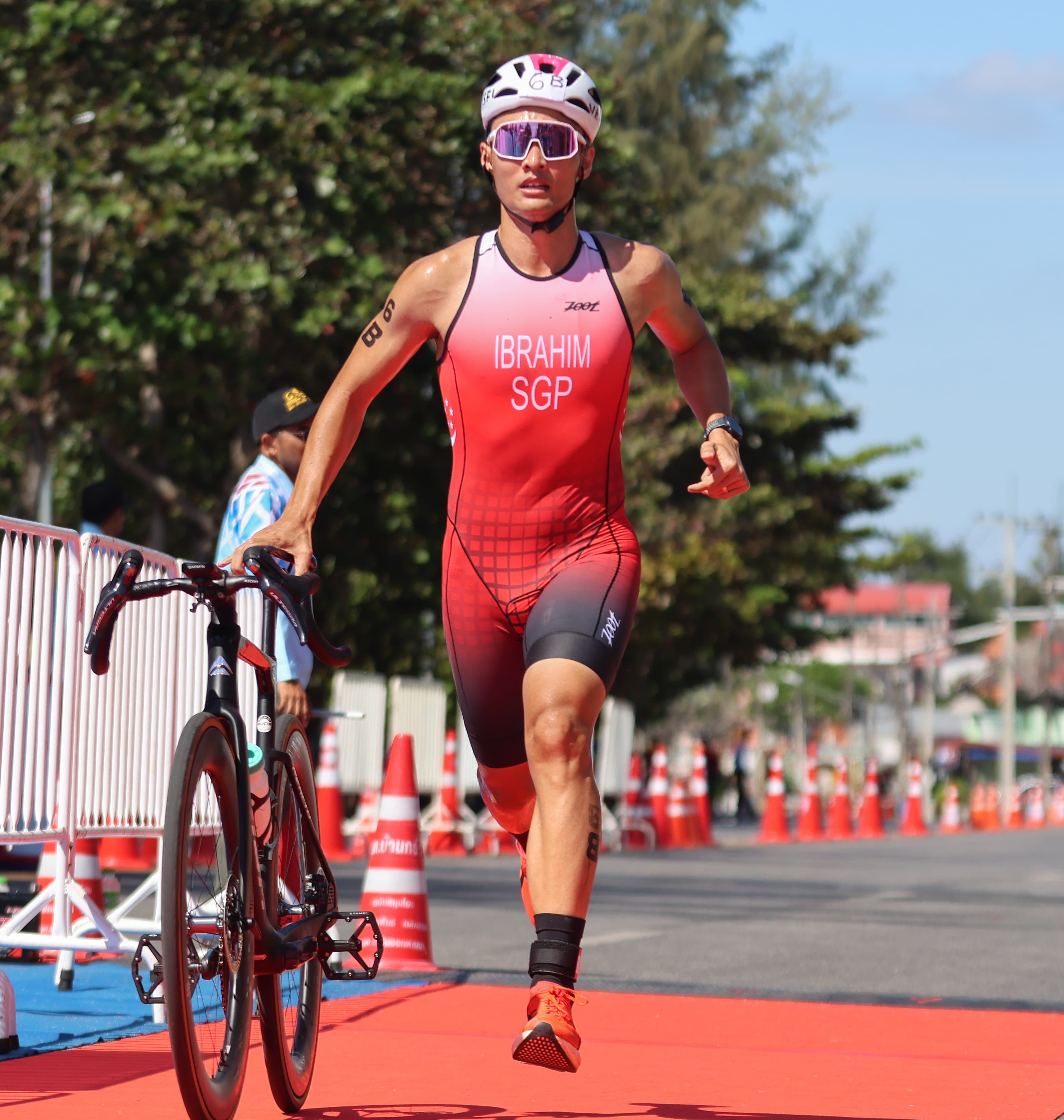 Mr Ahmad Arif Bin Ibrahim in red running suit running with his bicycle.