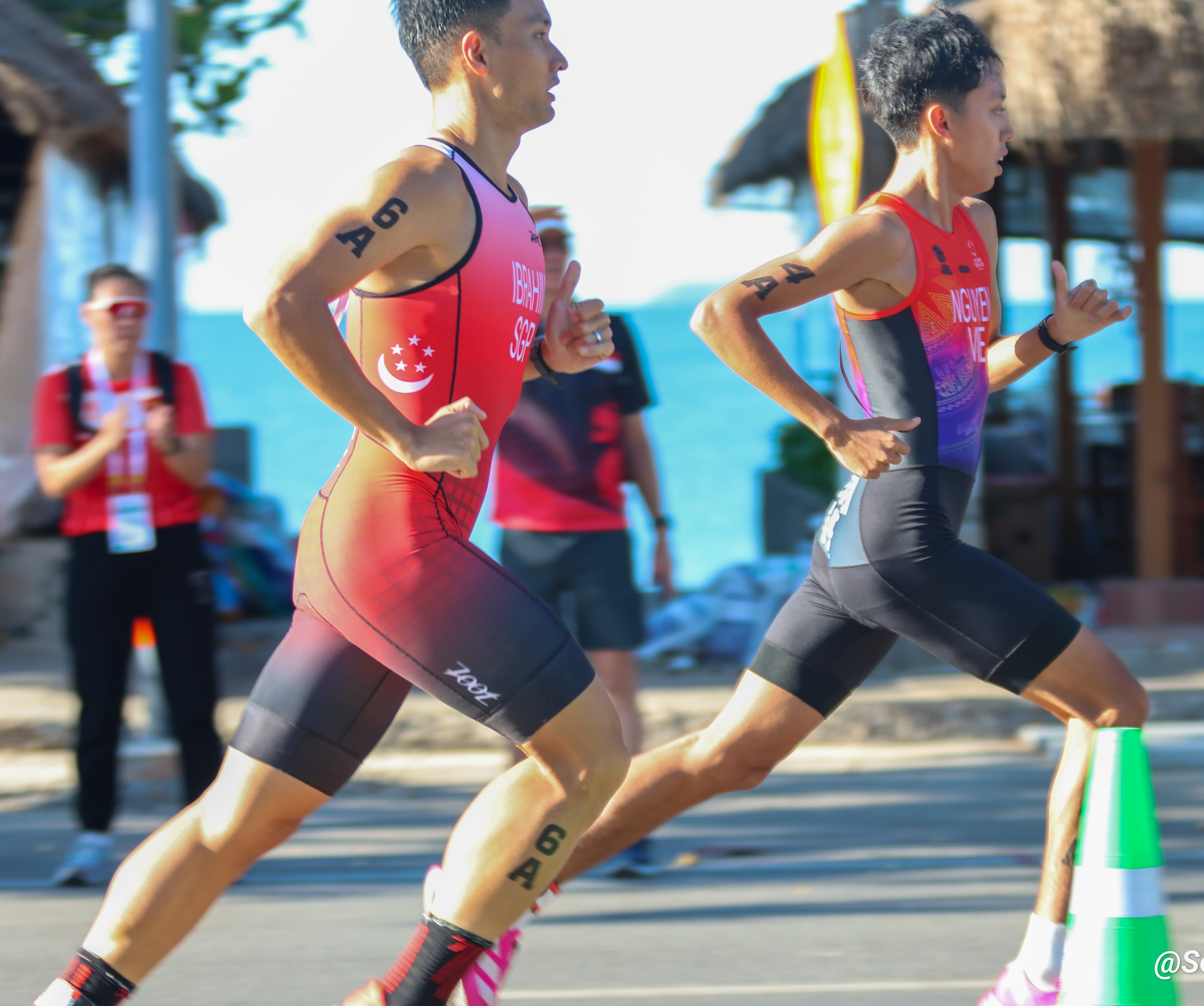 Mr Ahmad Arif Bin Ibrahim in red running suit printed 6A on right arm and leg competing closely against competitors.
