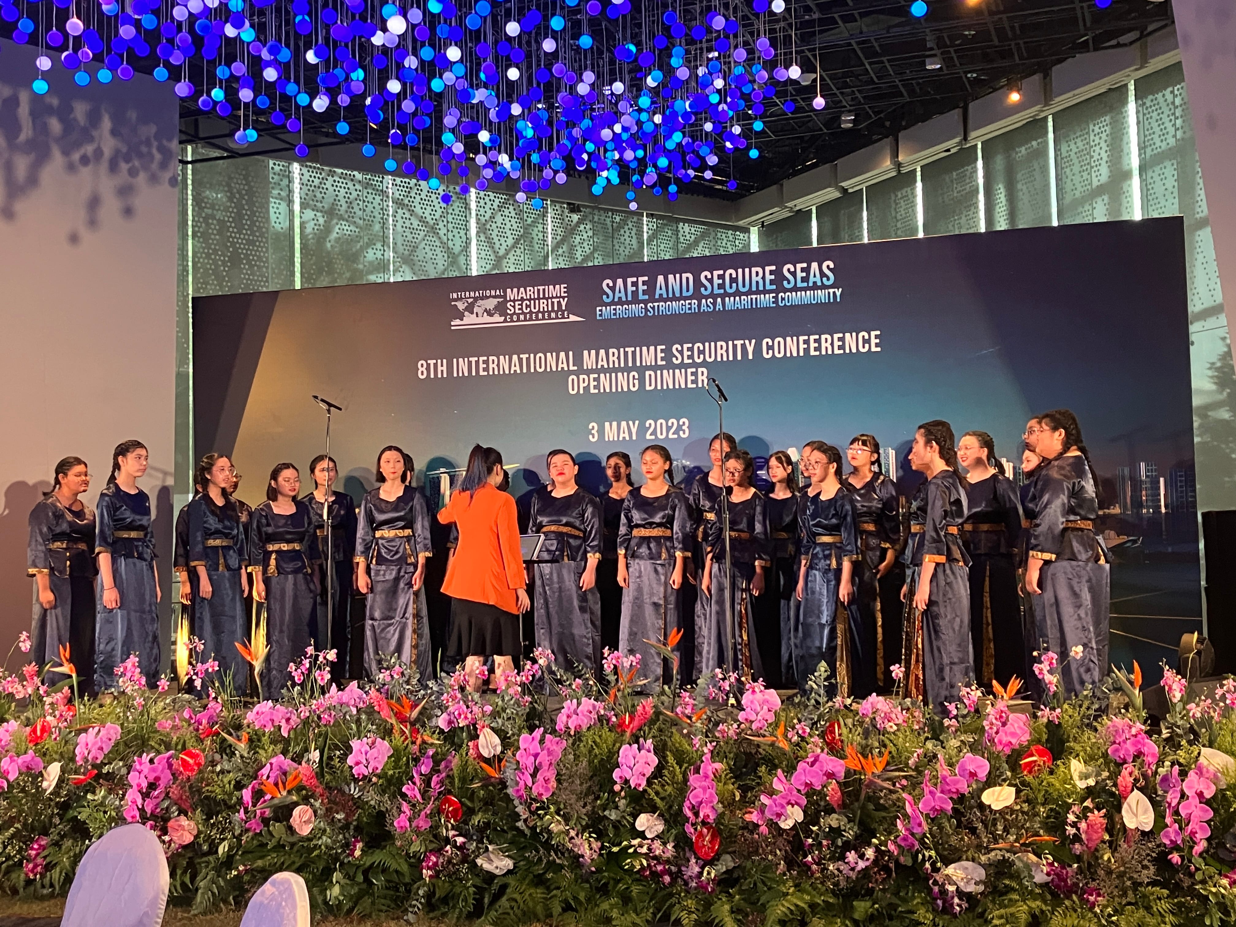 A choir in dark blue outfits performs on stage at the 8th International Maritime Security Conference opening dinner, May 3, 2023.