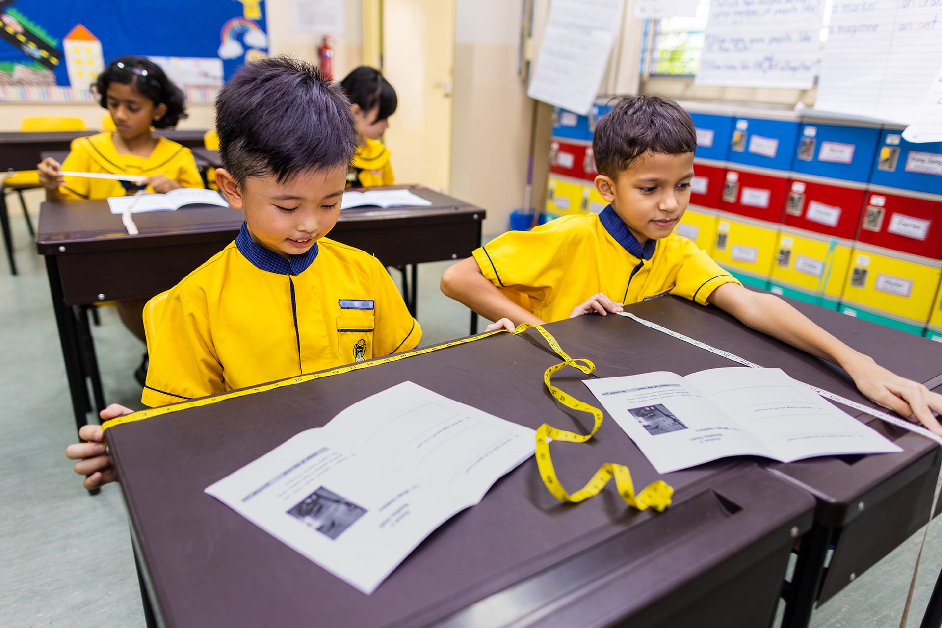 students measuring the dimension of student desk