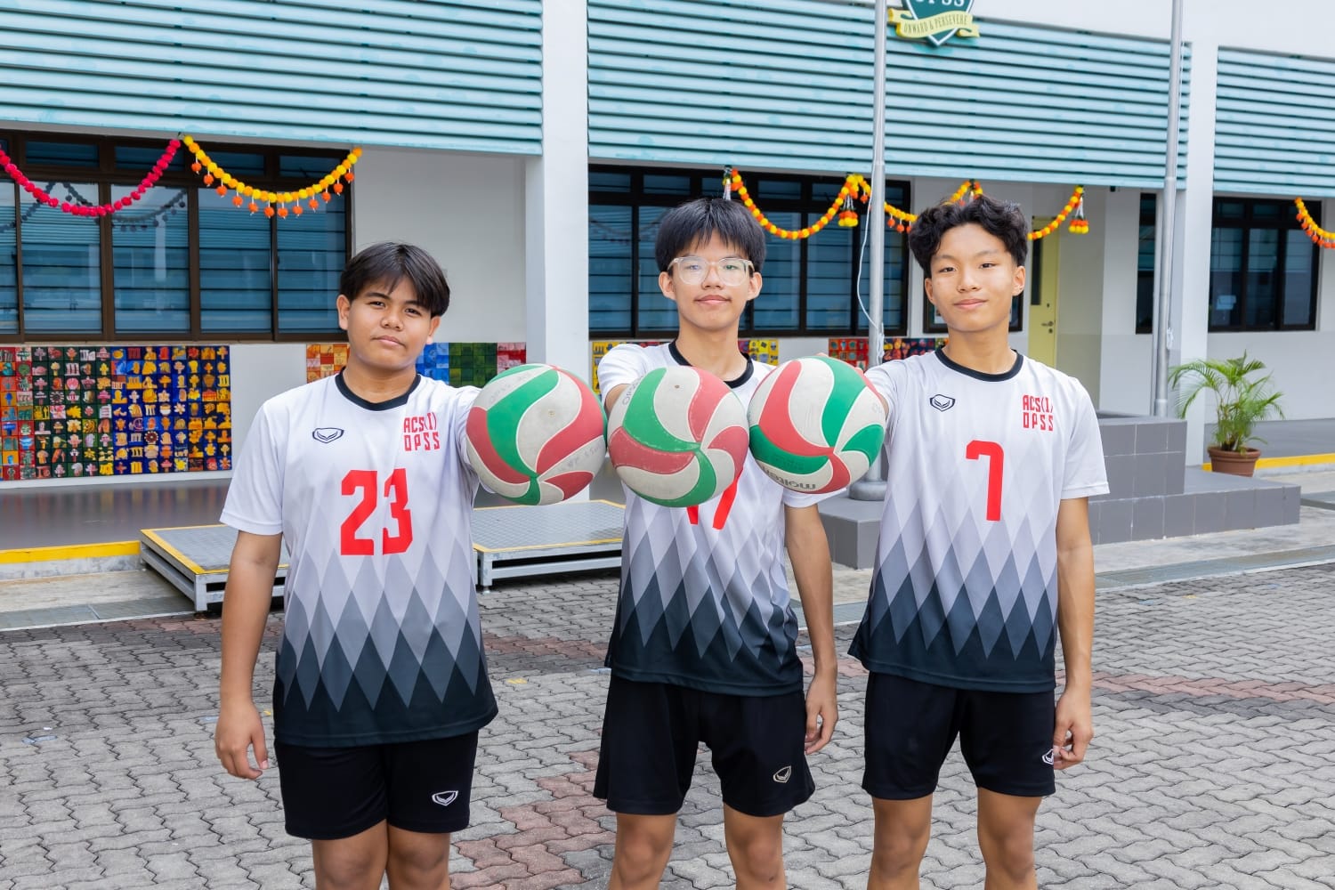 A posed shot of 3 volleyball players holding volleyballs