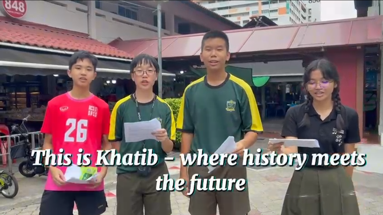 4 students standing in the middle of an HDB neighbouthood presenting about the neighbourhood of Khatib