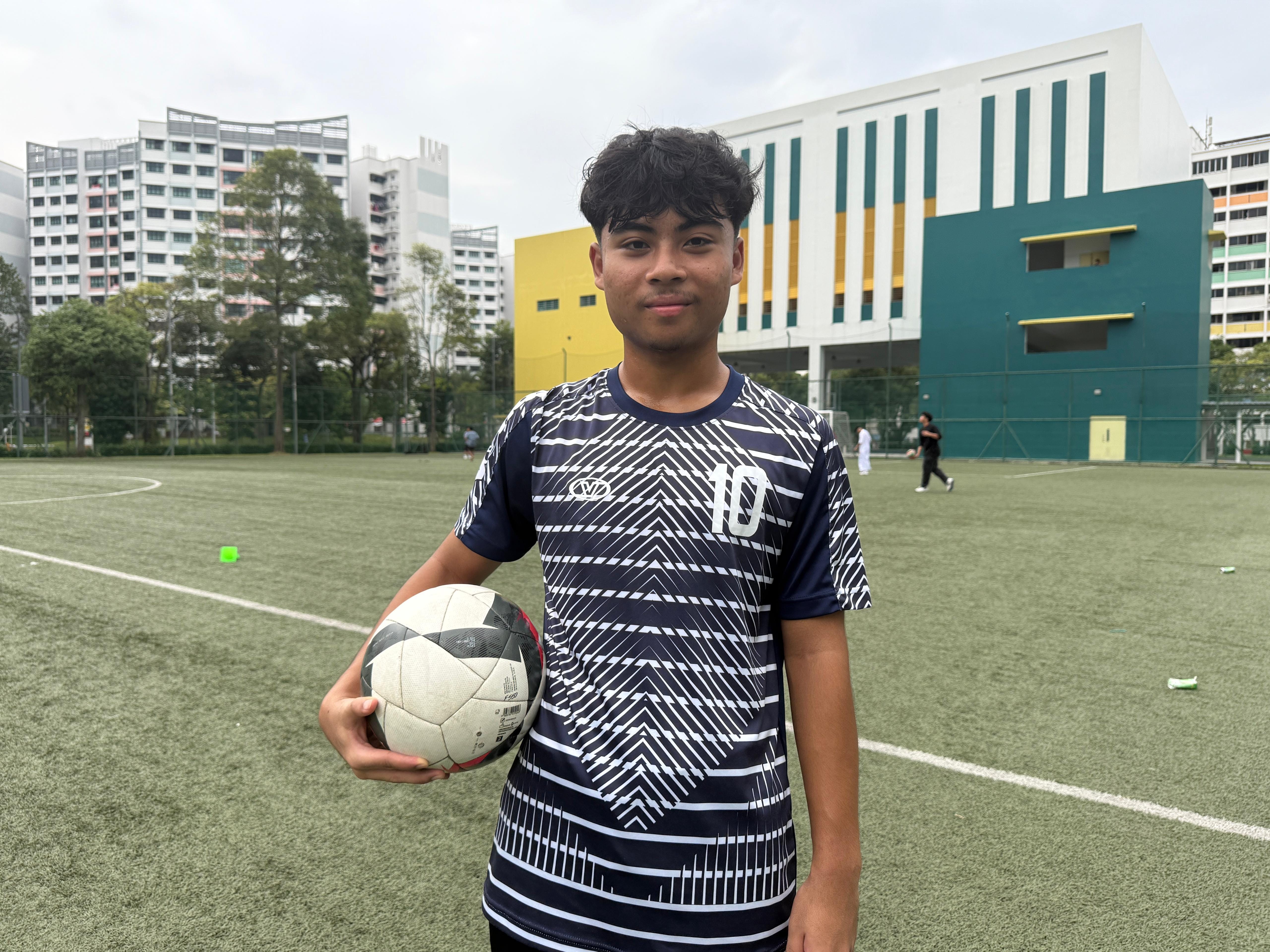 Student standing in the soccer pitch in his soccer jersey posing for a photo