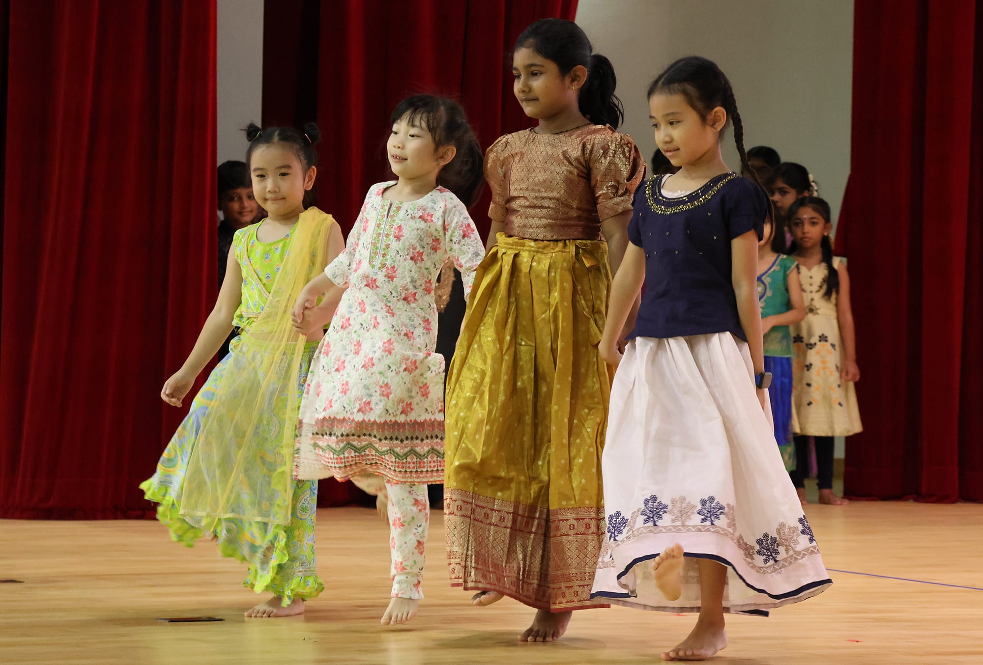 Students wearing traditional Indian costumes perform a coordinated folk dance during the school's Deepavali celebration, celebrating Singapore's multicultural heritage.