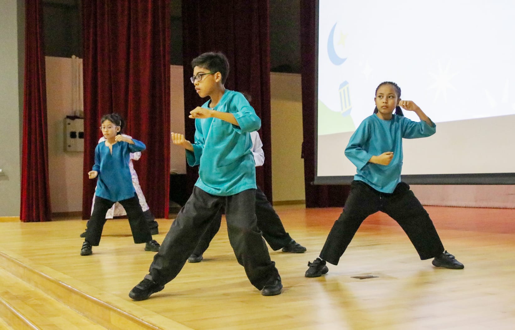 Students perform a silat demonstration on stage during the Hari Raya celebration, showcasing the traditional Malay martial art.