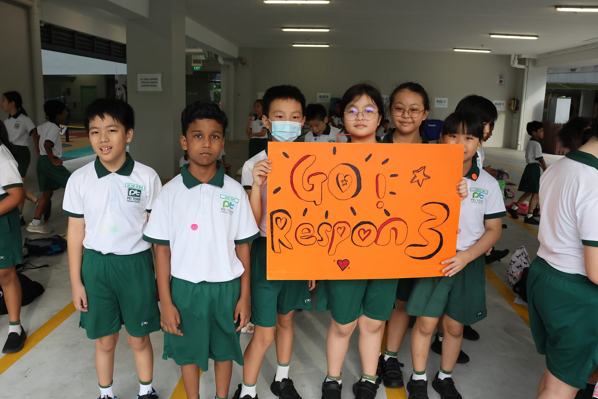 A group of students proudly hold a handmade "Go! Respon3" support banner, cheering on their classmates during the Sports Carnival.