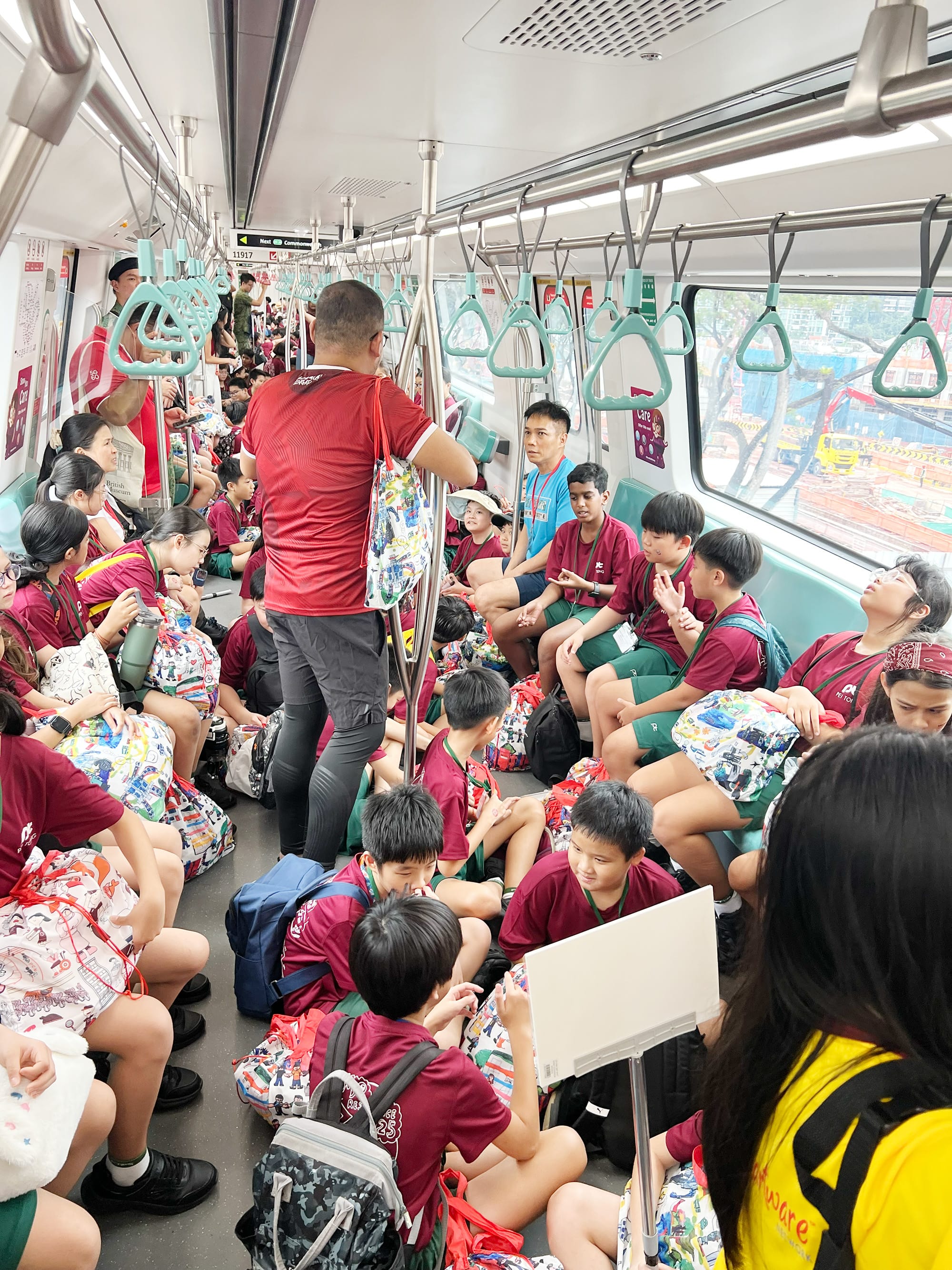 Primary 5 students travel together on the MRT to attend the National Education Show, preparing for a day of learning and celebration.