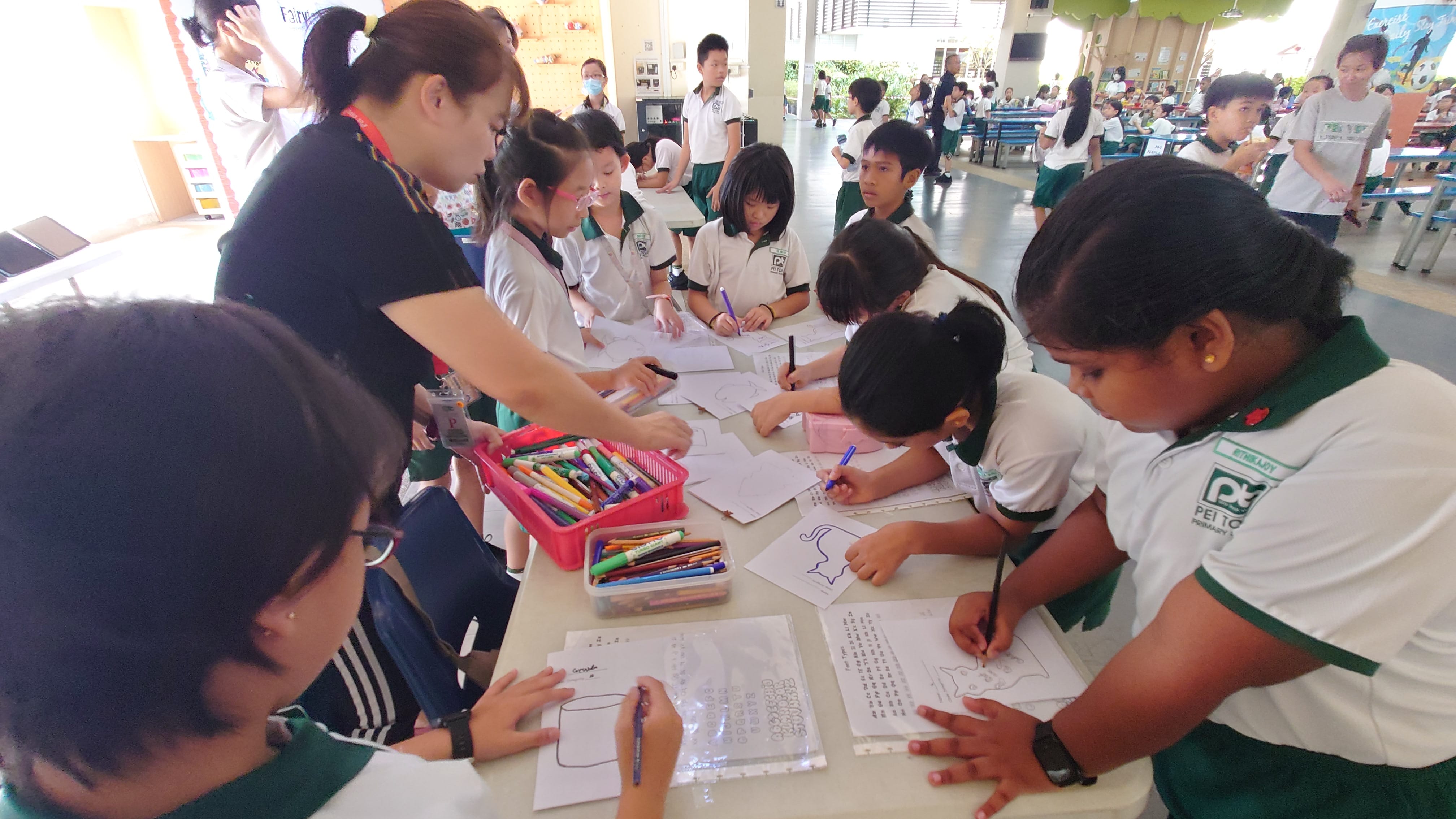Students participating in work together on drawing and writing tasks guided by our parent volunteer in the school canteen.