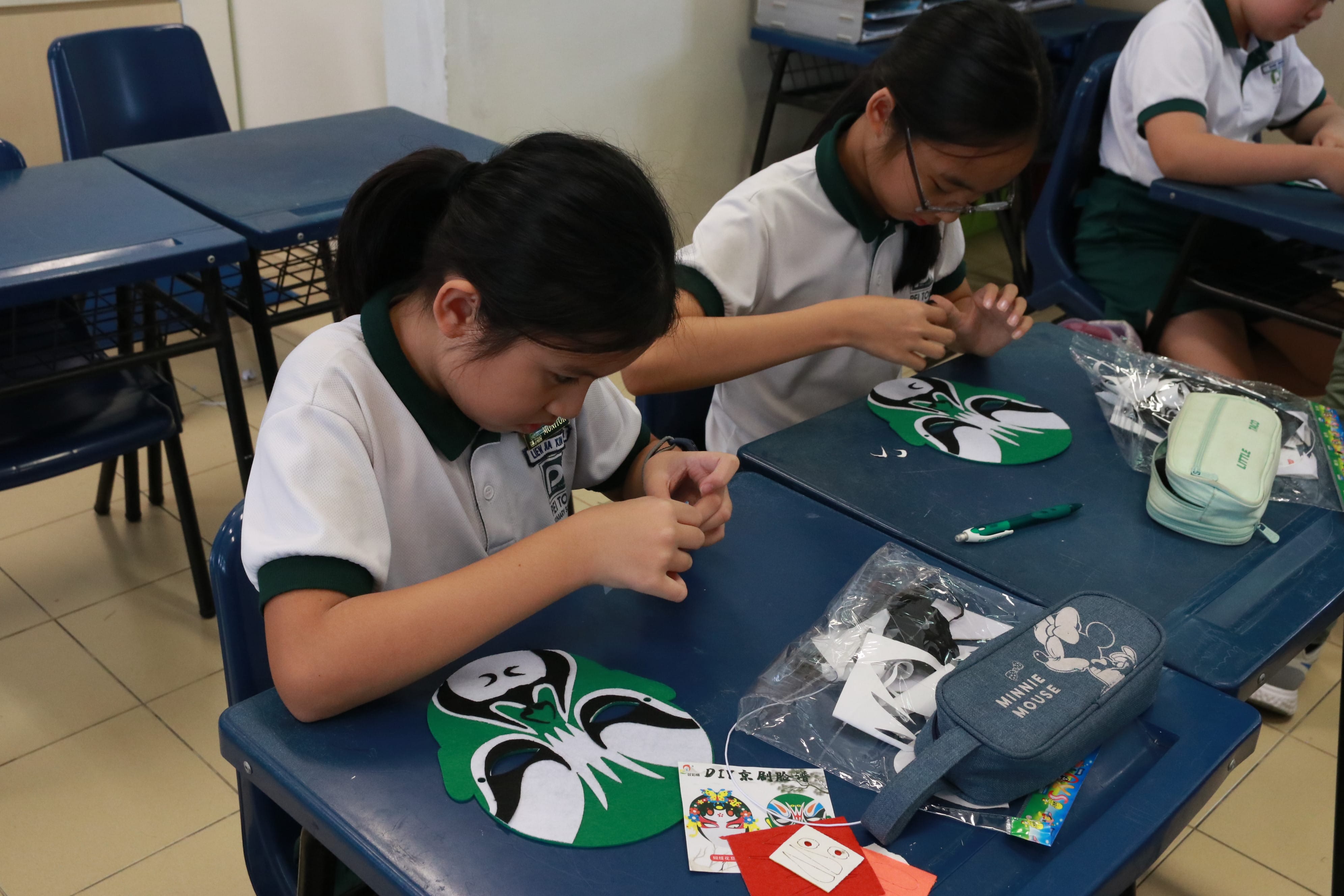 Students carefully creating traditional mask crafts together