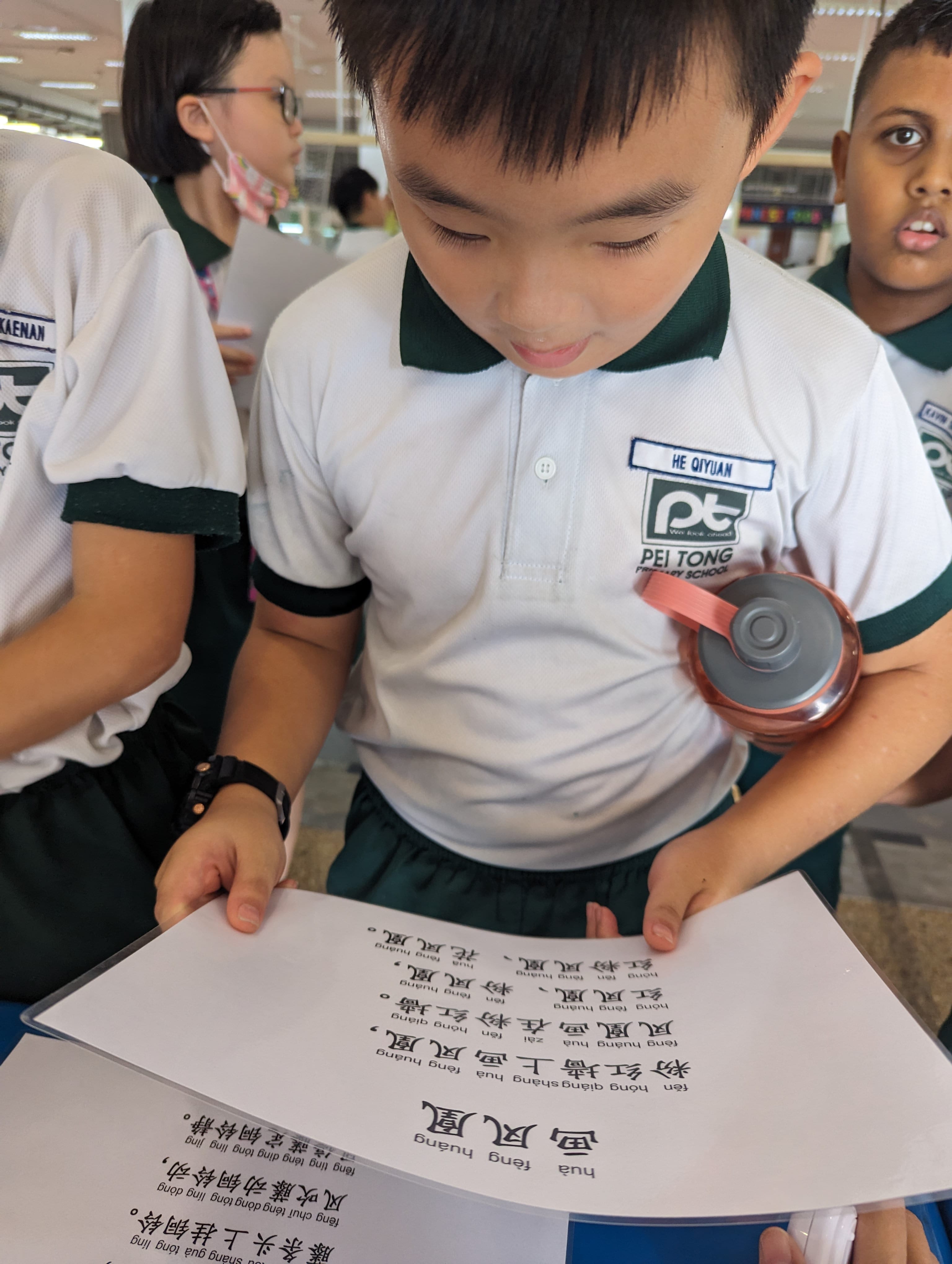 Student concentrating on a Chinese tongue twister sheet while participating in the 绕口令挑战 (Tongue Twisters Challenge), developing confidence in spoken Chinese.