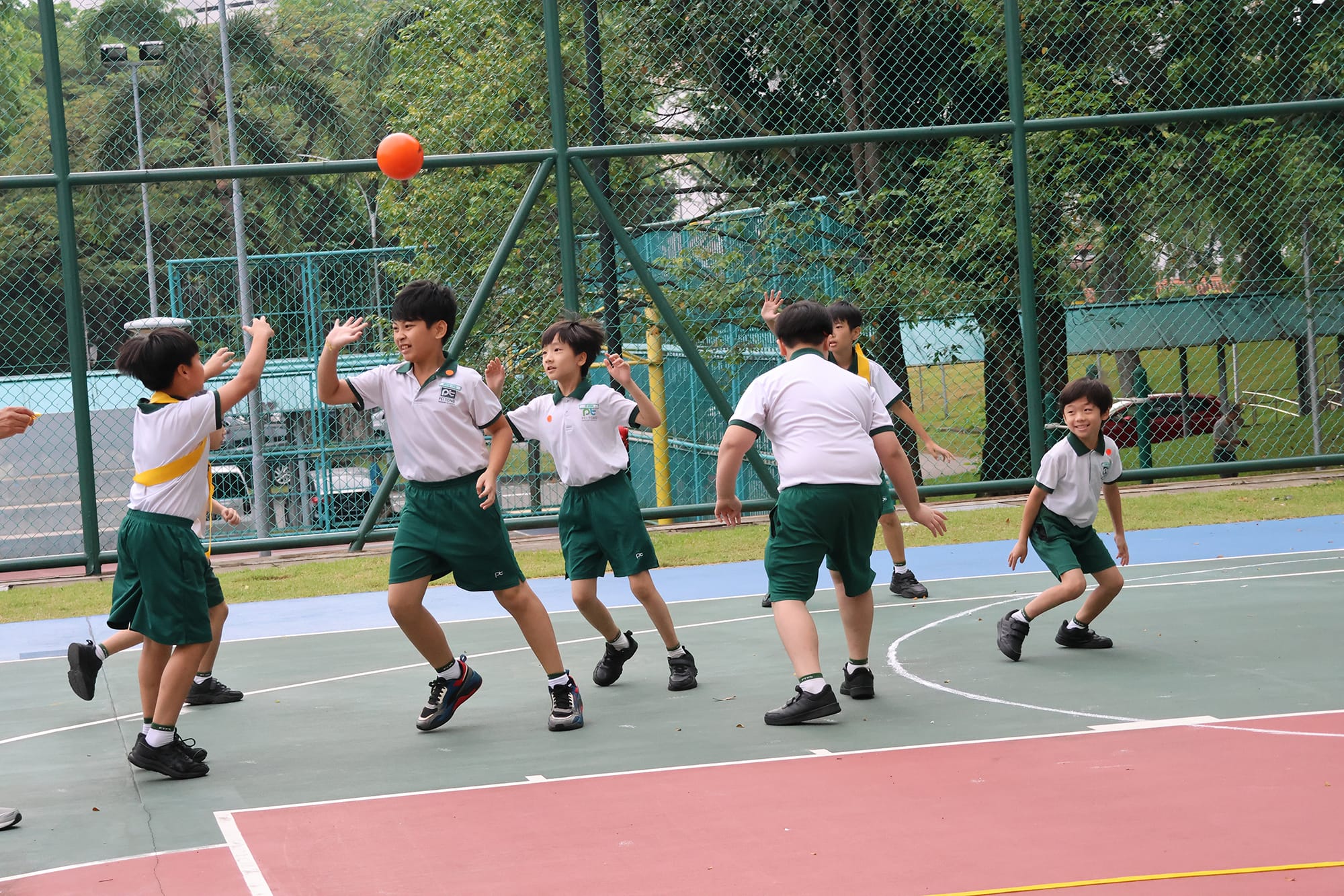 Students play a lively game of captain's ball on the outdoor court, jumping, passing, and defending as teammates work together during the Sports Carnival.