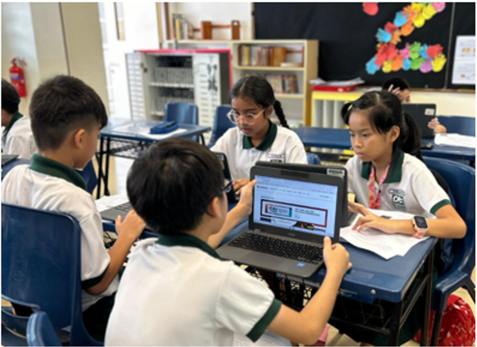 Four students collaborating in the classroom using Chromebooks, as they engage in discussion and digital learning activities to develop critical thinking and problem-solving skills.