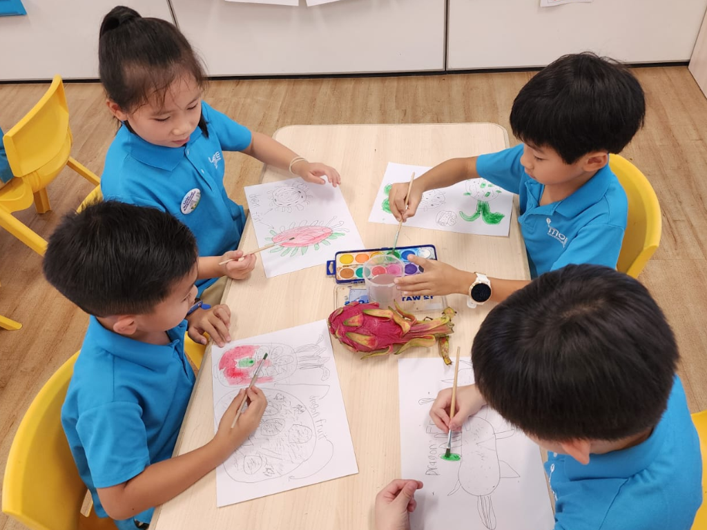 Children paint and colour fruit illustrations while observing real fruits, encouraging creativity, language development and appreciation of the natural world.