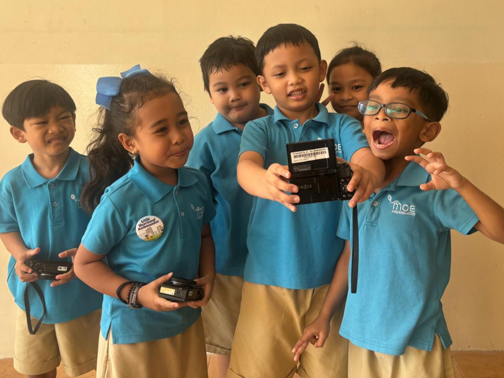 Kindergarten children use digital cameras to photograph their surroundings as they document observations and investigate a topic together.