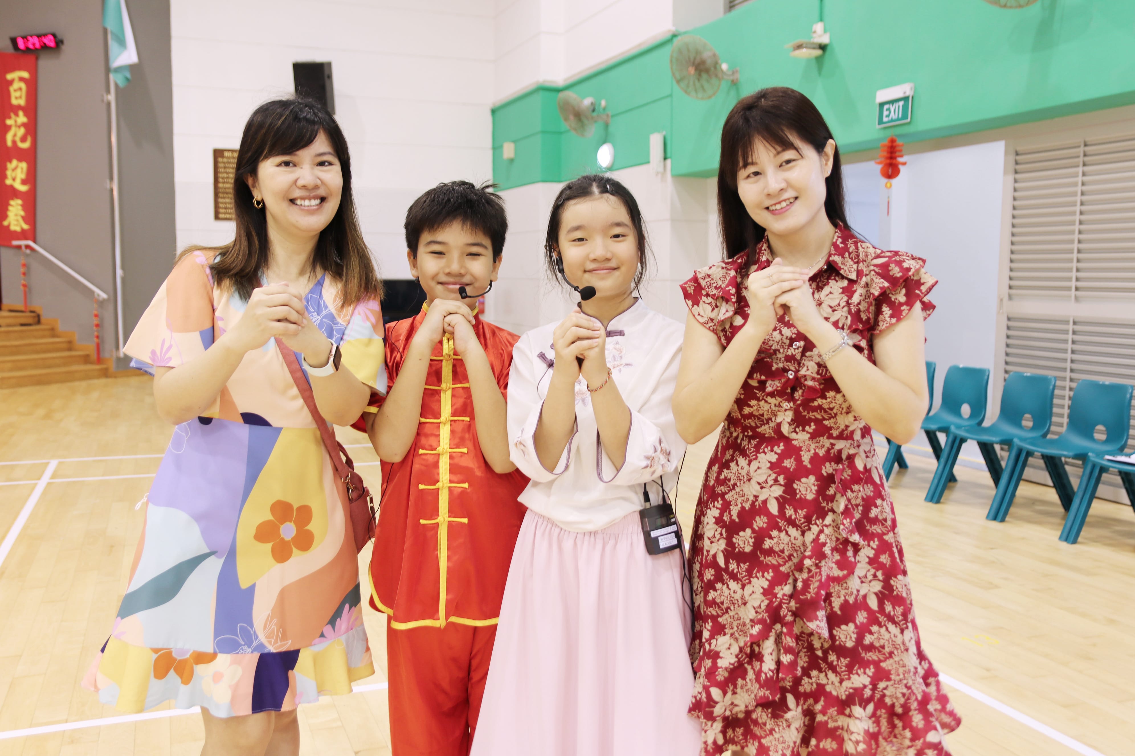 Teachers and student emcees dressed in festive attire pose together during the school's Chinese New Year celebration.