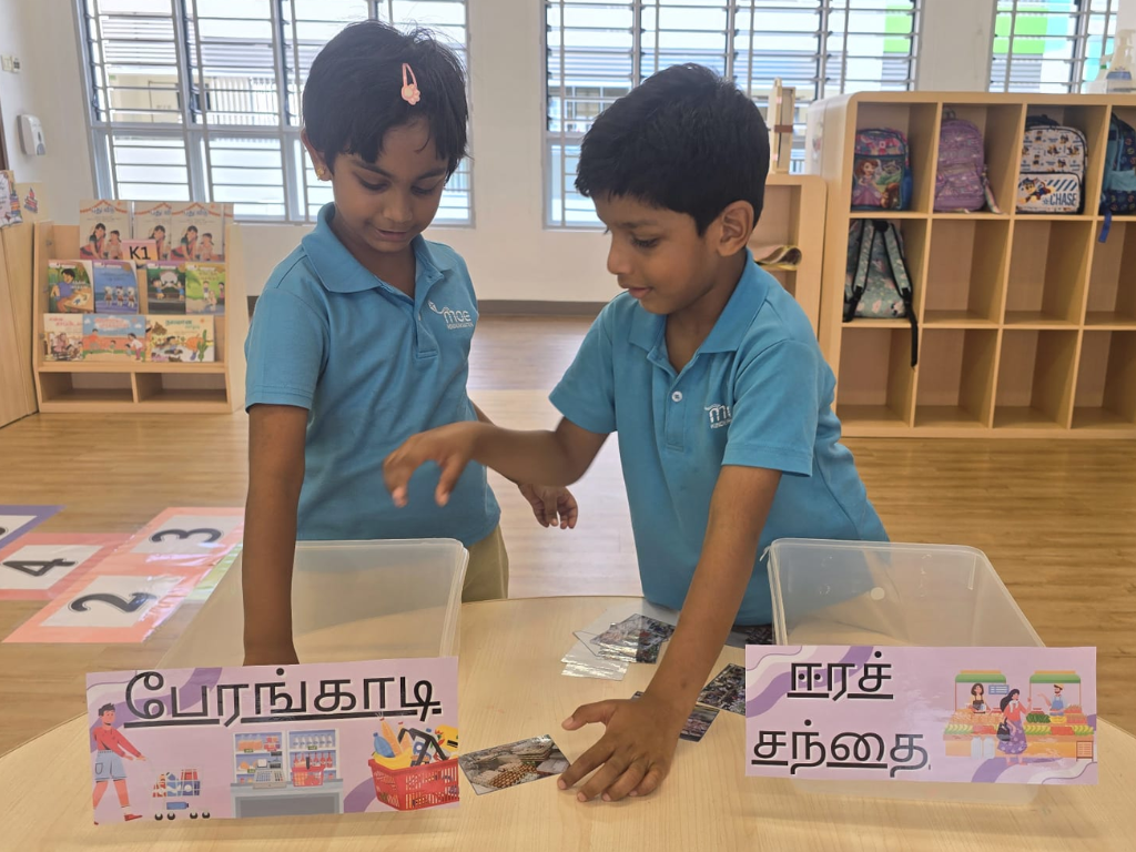 Children sort picture cards into categories during a language activity, developing vocabulary and literacy skills through hands-on learning in their Mother Tongue language.
