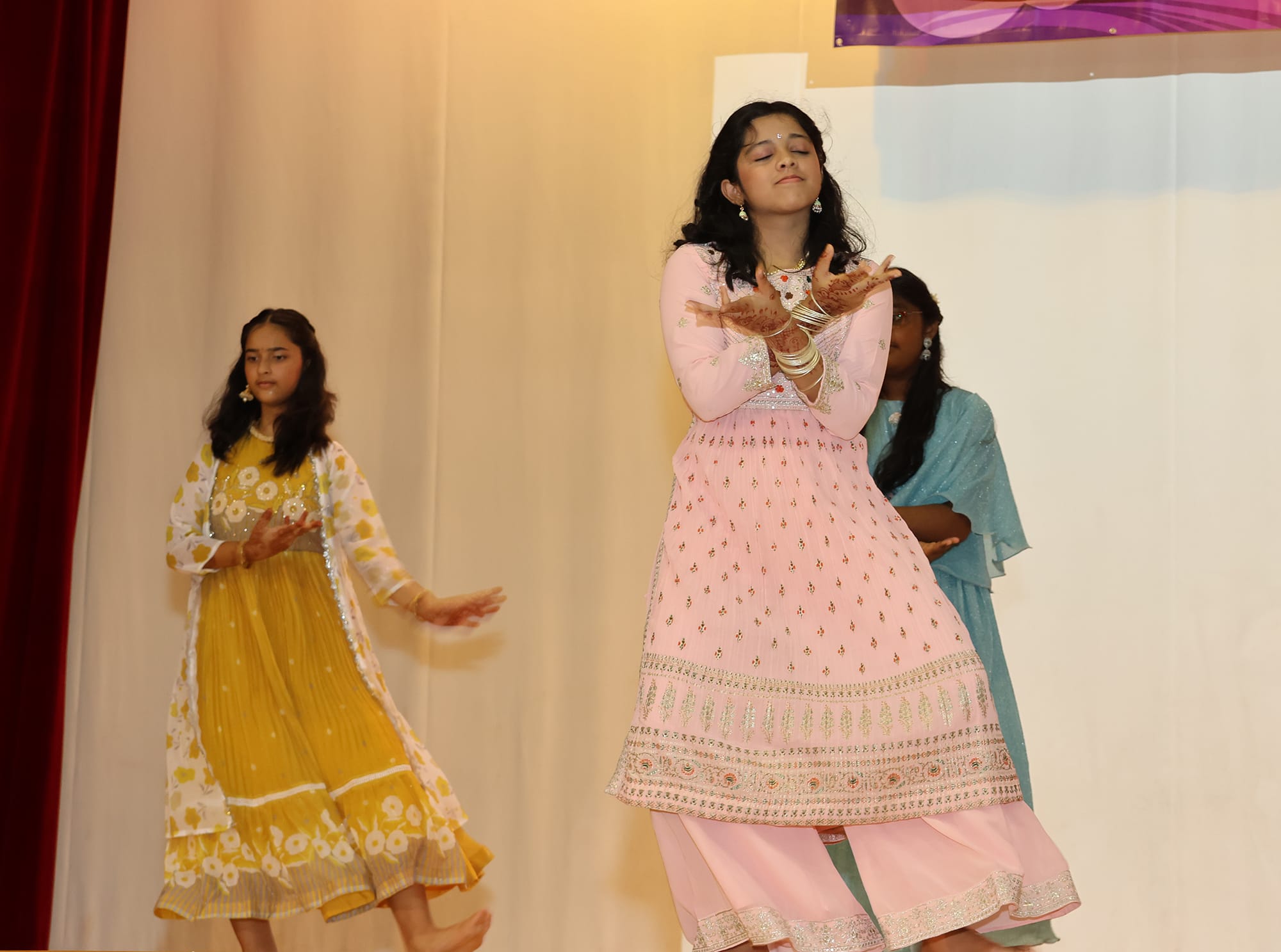 Students perform a traditional Indian dance on stage during the school's Deepavali celebration, showcasing cultural heritage through music and movement.