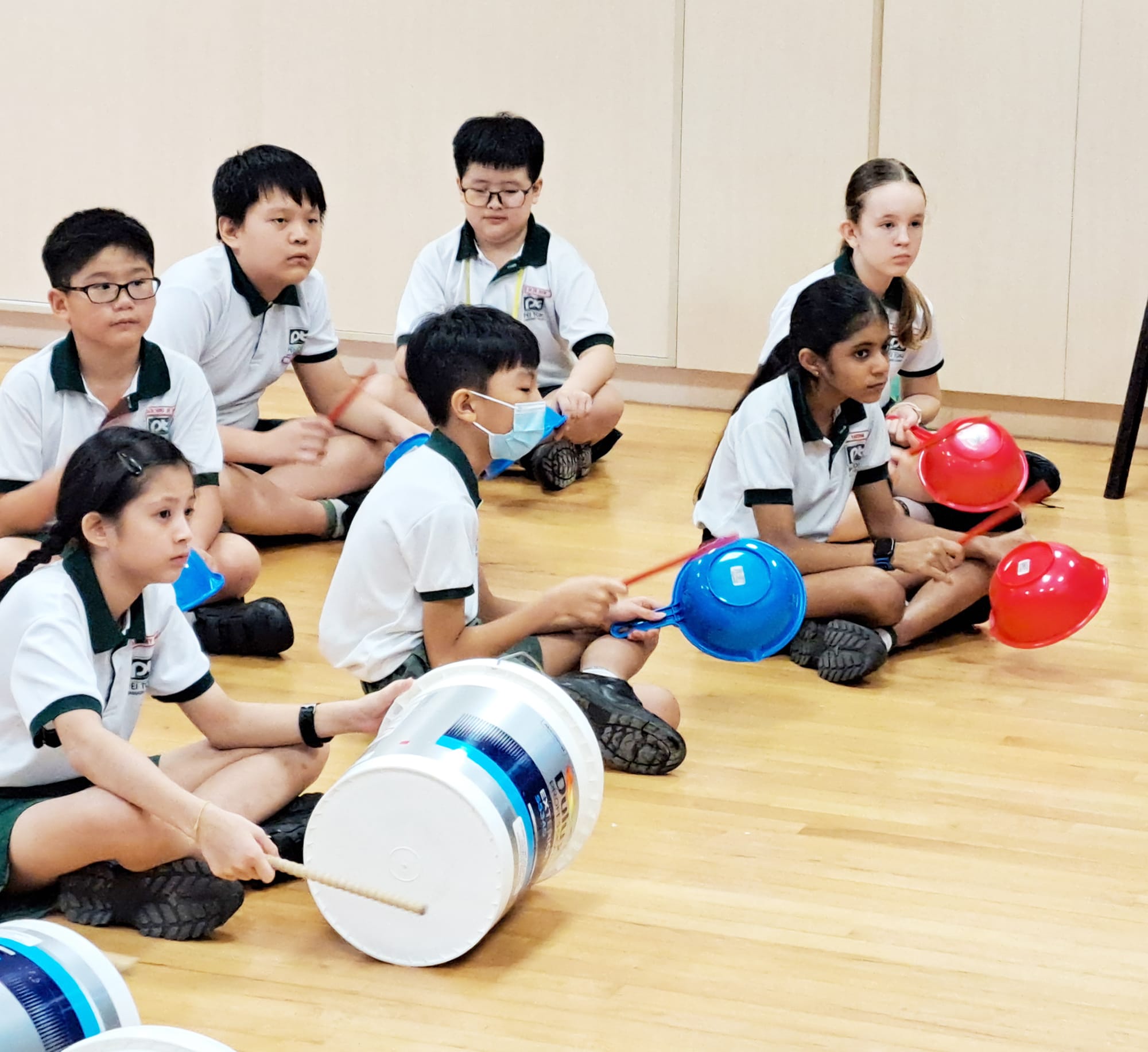 Students use buckets and everyday objects as percussion instruments during a STOMP workshop, exploring rhythm, coordination and teamwork through music.