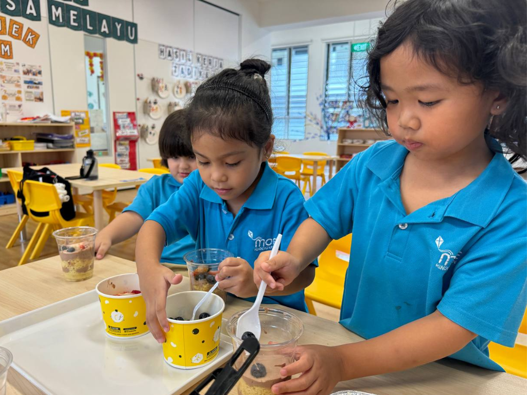 Children work together to prepare and observe food ingredients, sharing ideas and recording their discoveries during a hands-on project.