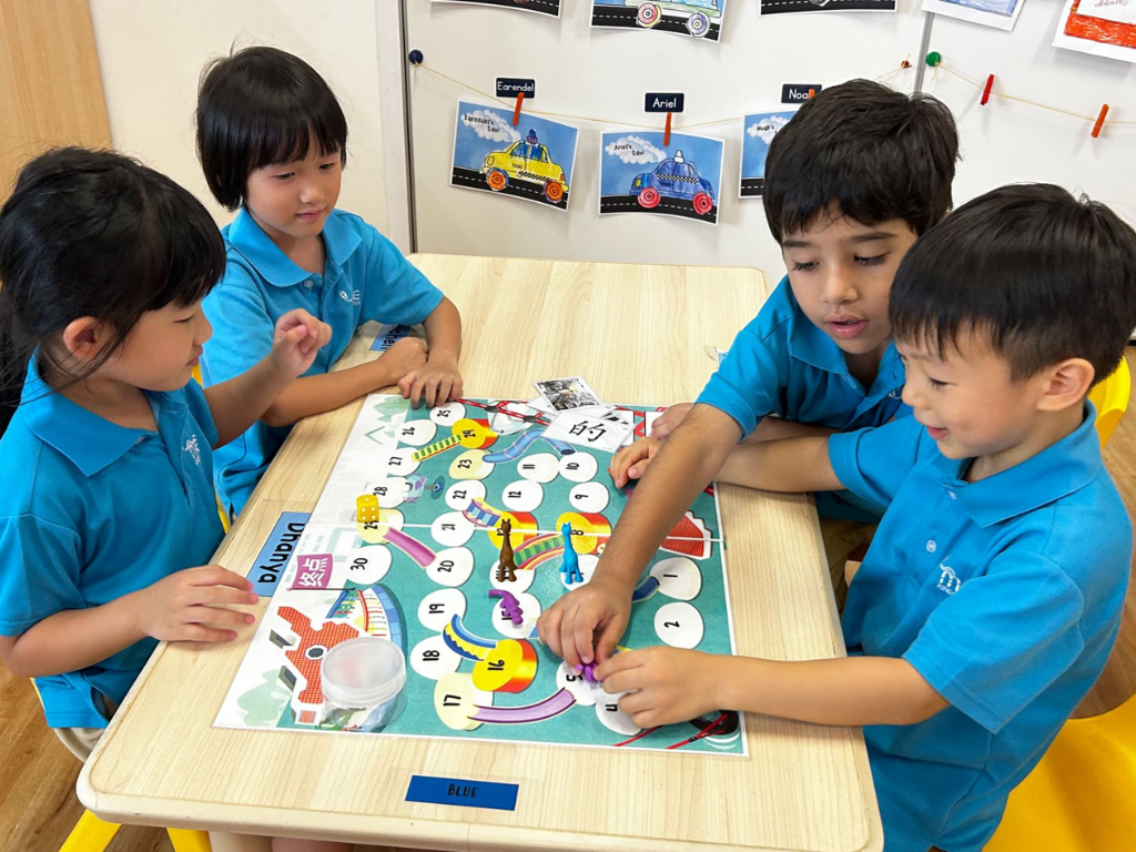 Children play a literacy board game together, taking turns to practise speaking, listening and early reading skills through play.
